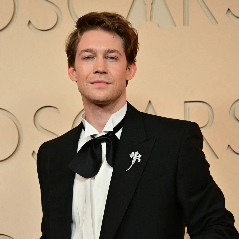 <p>Joe Alwyn wears Chaumet <i>Œillet brooch</i> in white gold, set with brilliant-cut diamonds</p>