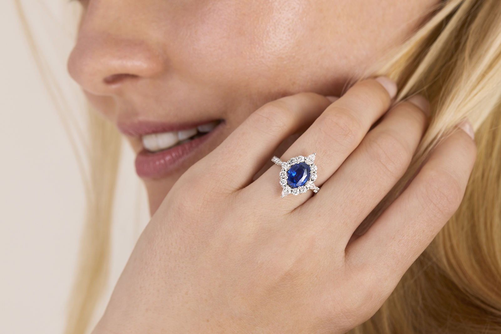 Taylor & Hart oval blue sapphire engagement ring with a round and pear-shaped diamond halo and pavé diamond band