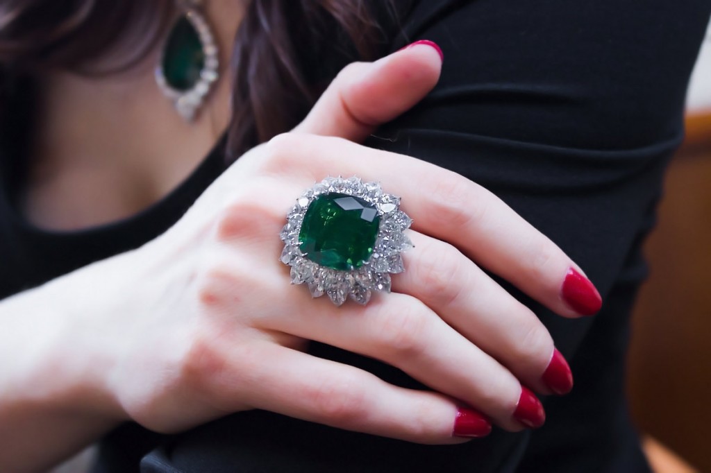 A ring centered upon a gem quality 22cts cushion-cut Colombian emerald set within a double row of pear-shaped diamonds