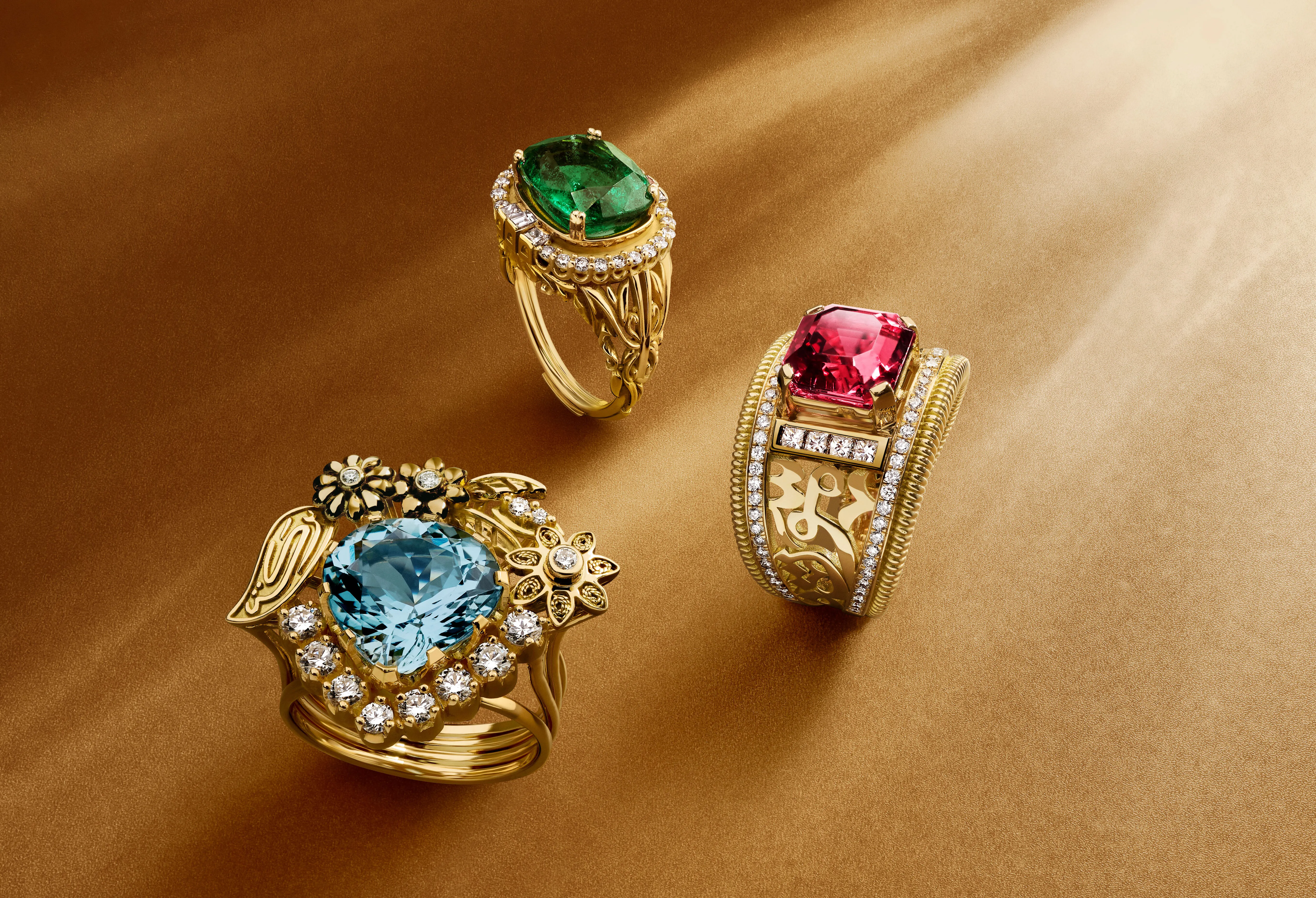 A trio of Azza Fahmy rings from the Tales of the Nile High Jewellery collection, including the Garden of Light ring with a pear-shaped aquamarine (left) and the Art Deco Calligraphy ring (right) with a 3.97-carat rubellite, both in yellow gold 