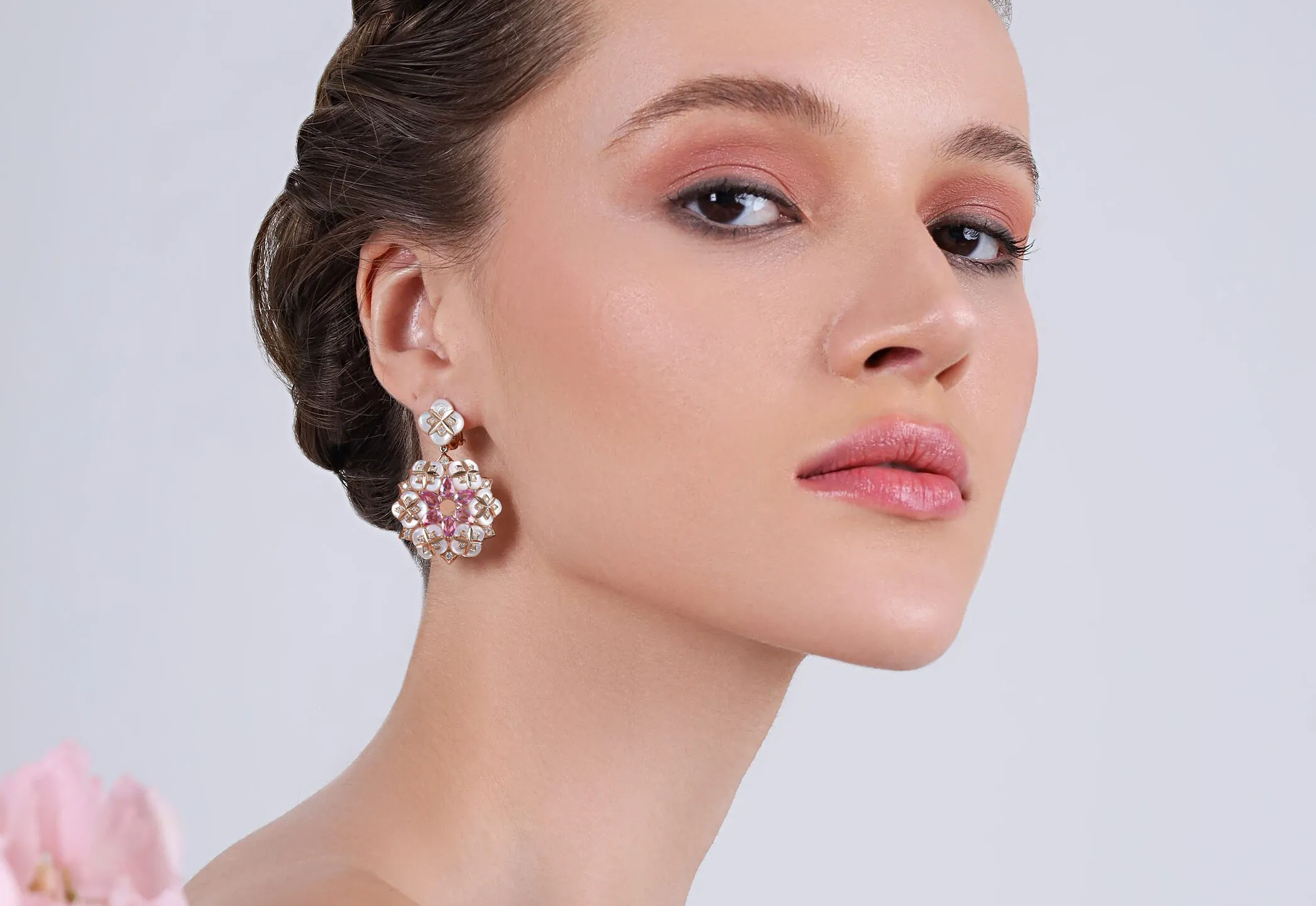 A model wears earrings from the BijouQ Flora Geomatrica collection with mother of pearl and diamonds in 18k rose gold 