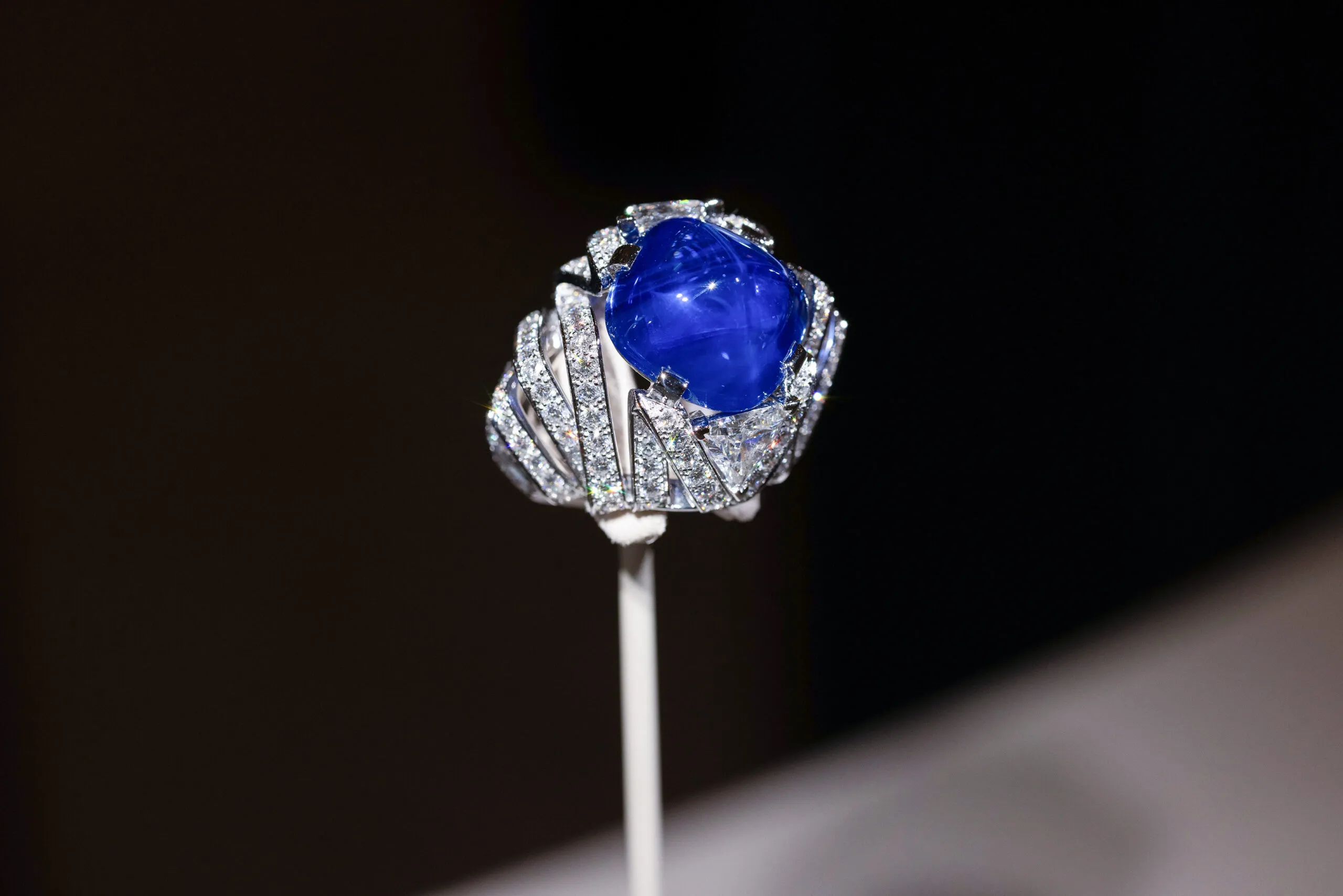 Cartier ring with a 21.69-carat antique cushion-shaped cabochon-cut sapphire and two triangular-shaped modified brilliant-cut diamonds totalling 1.89 carats, set in platinum, part of the En Équilibre High Jewellery collection