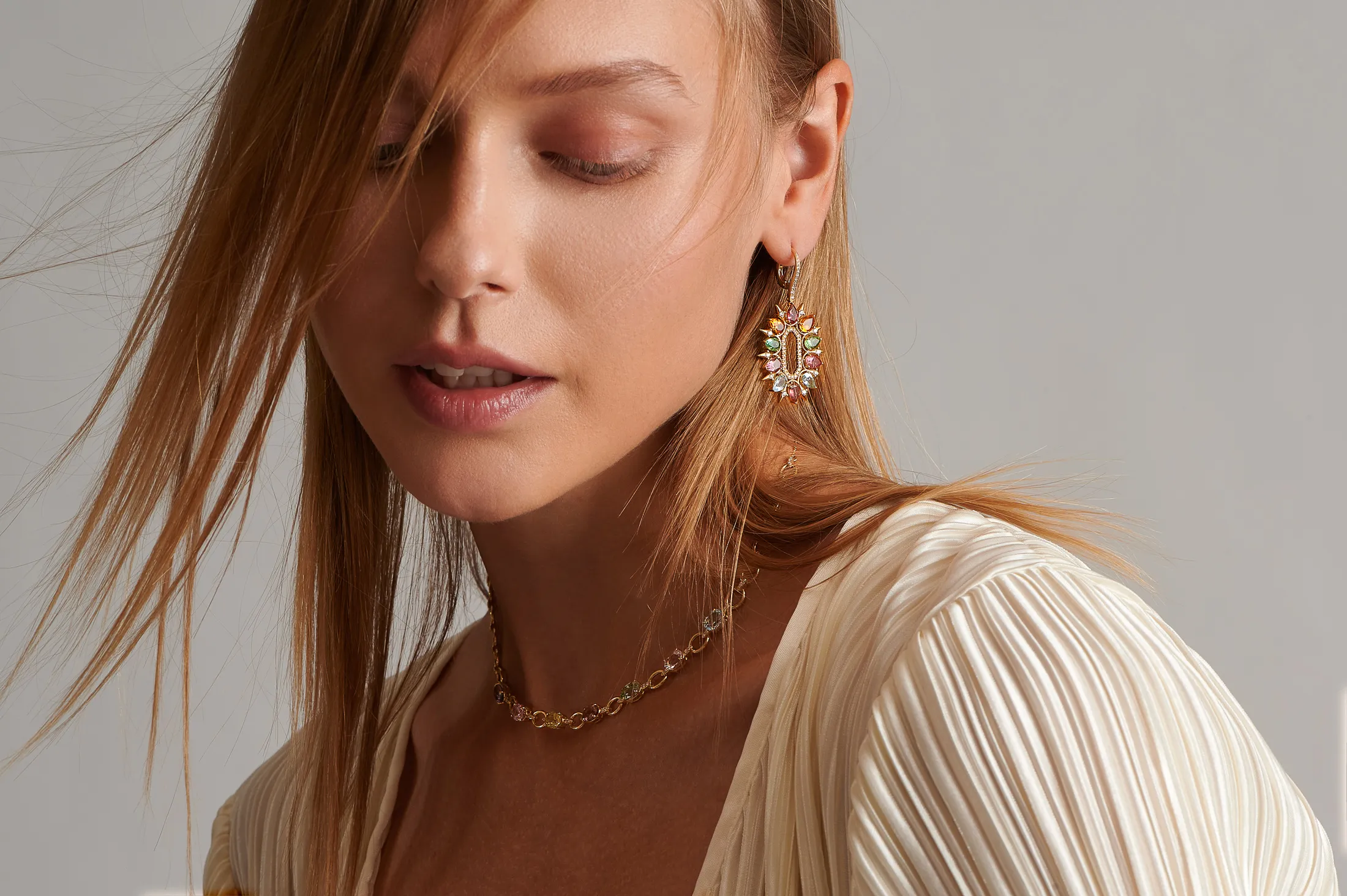 A model wears pieces from the Kalypso collection by Dionysios Fine Jewels, set with multi-coloured oval-cut and pear-shaped gemstones in 18k yellow gold