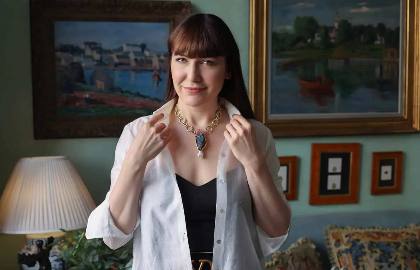 Katerina Perez wears the Labradorite Parrot pin by Elizabeth Gage as a necklace with a 108.46 carat carved labradorite body, pink tourmaline beak and head crest, rock crystal eyes, and a white-grey cultured keshi pearl in 18k yellow gold