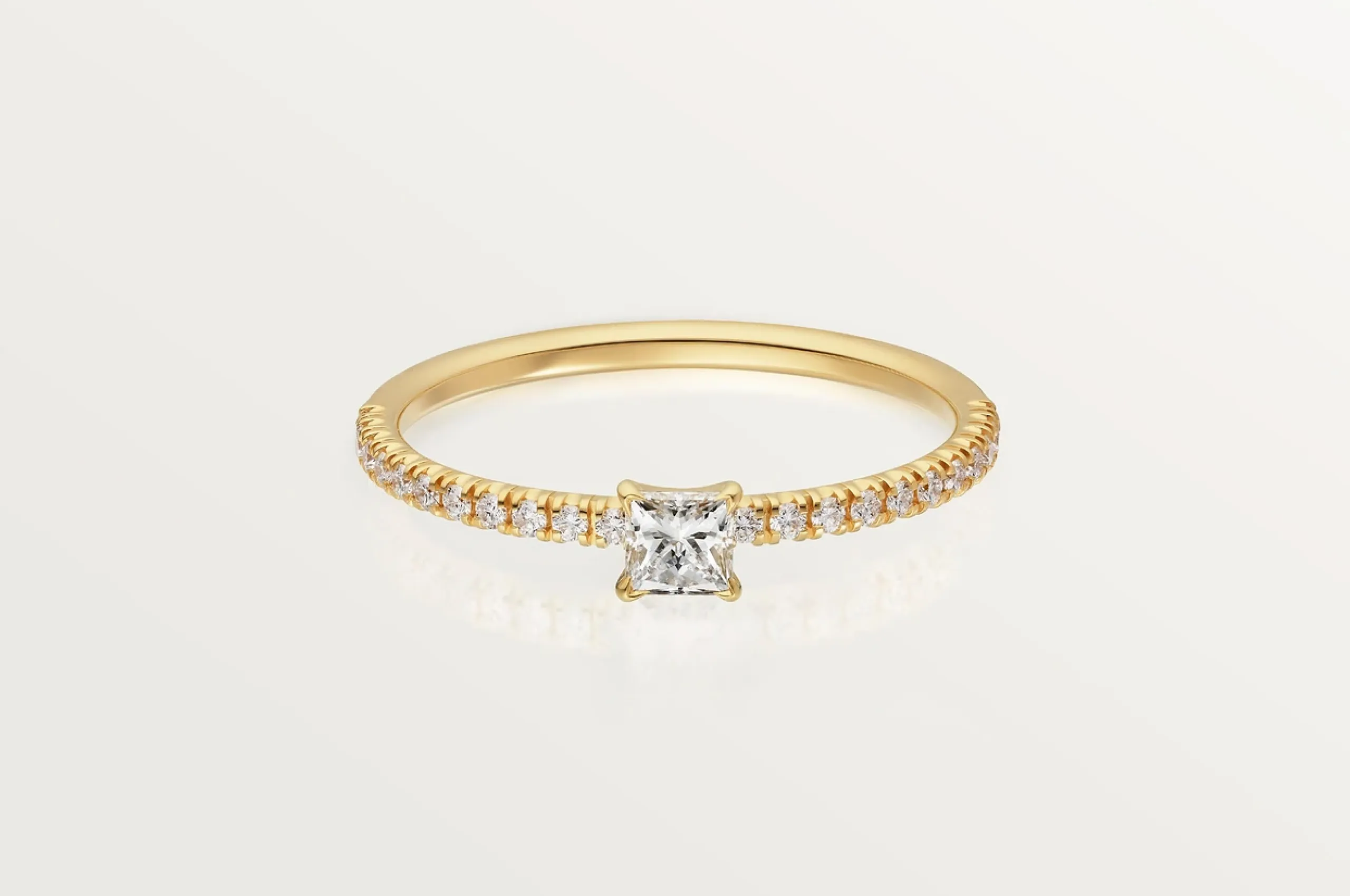 Cartier's dainty Etincelle de Cartier princess cut diamond ring in 18K yellow gold won't outshine your future engagement ring.