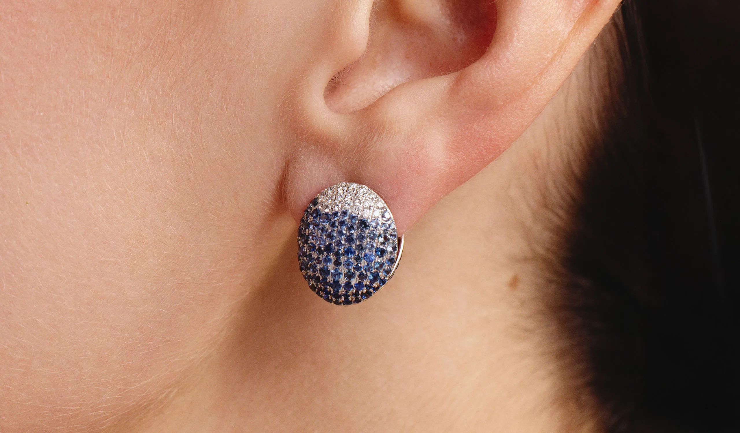 A model wears a pair of Yami reversible oval-shaped earrings with sapphires and diamonds by Gyan Jaipur