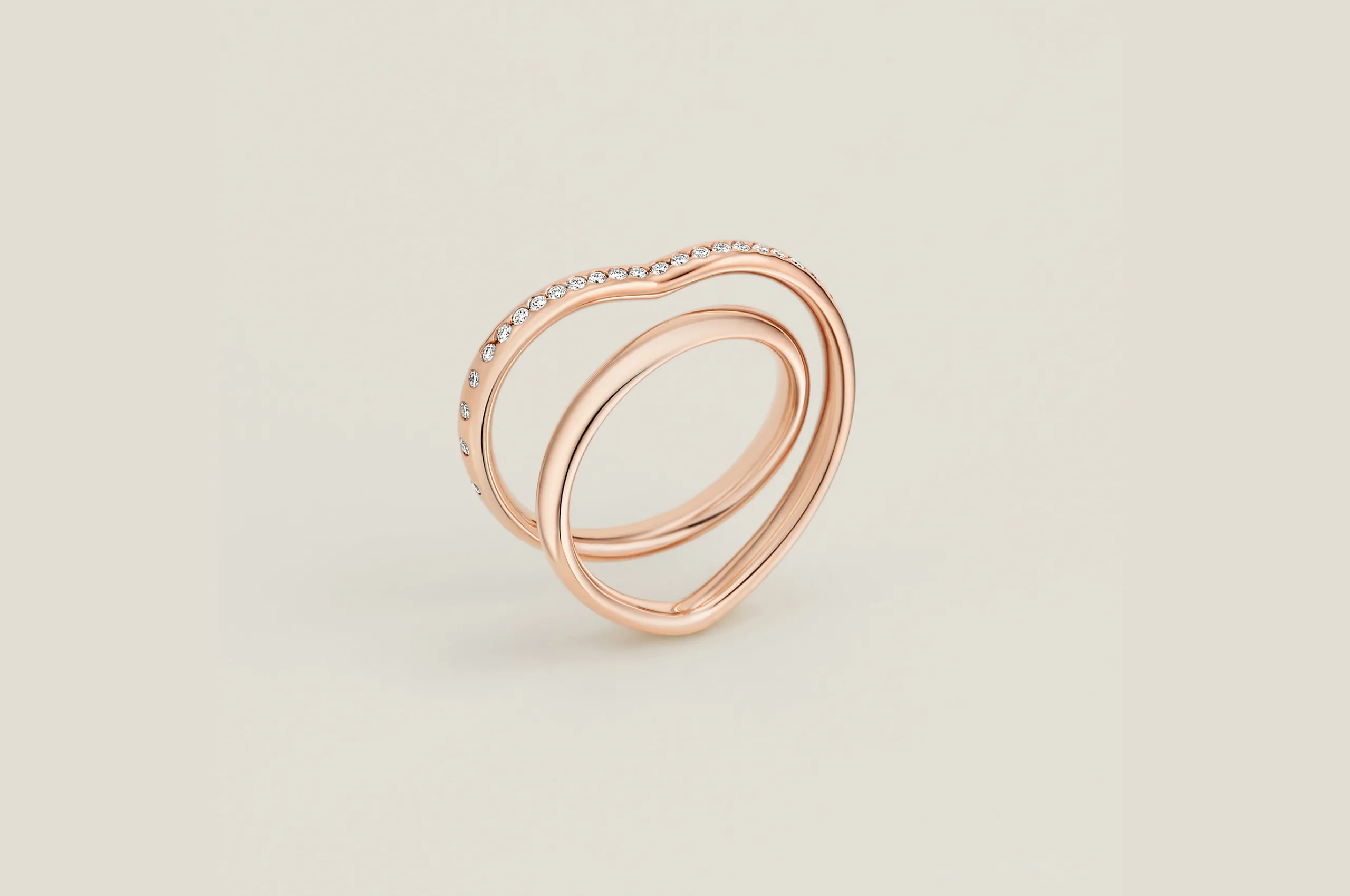 The Hermès Vertige Cœur ring in 18K rose gold with diamonds wraps around the finger to trace a heart shape.
