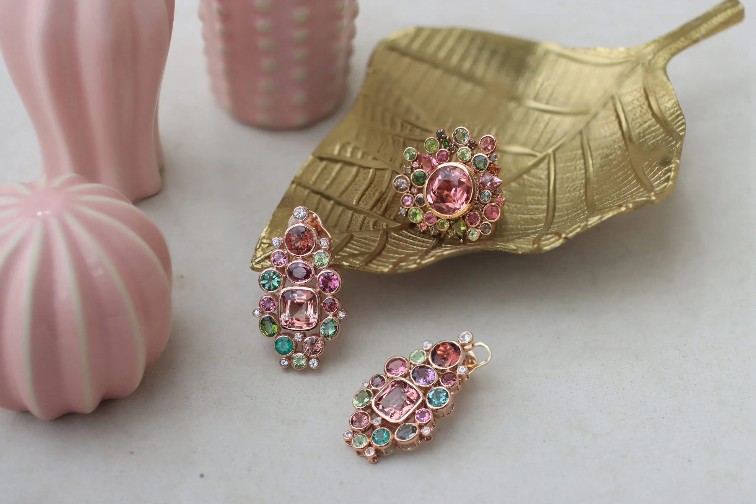 Zome Jewellery Coralene earrings from the Axia collection with 7.8 carats of pink tourmalines, multi-coloured tourmalines, emeralds and white sapphires, alongside the Vera ring from the Anthia collection with a 7.2 carat peach-pink tourmaline and further tourmalines, both in 18k rose gold 