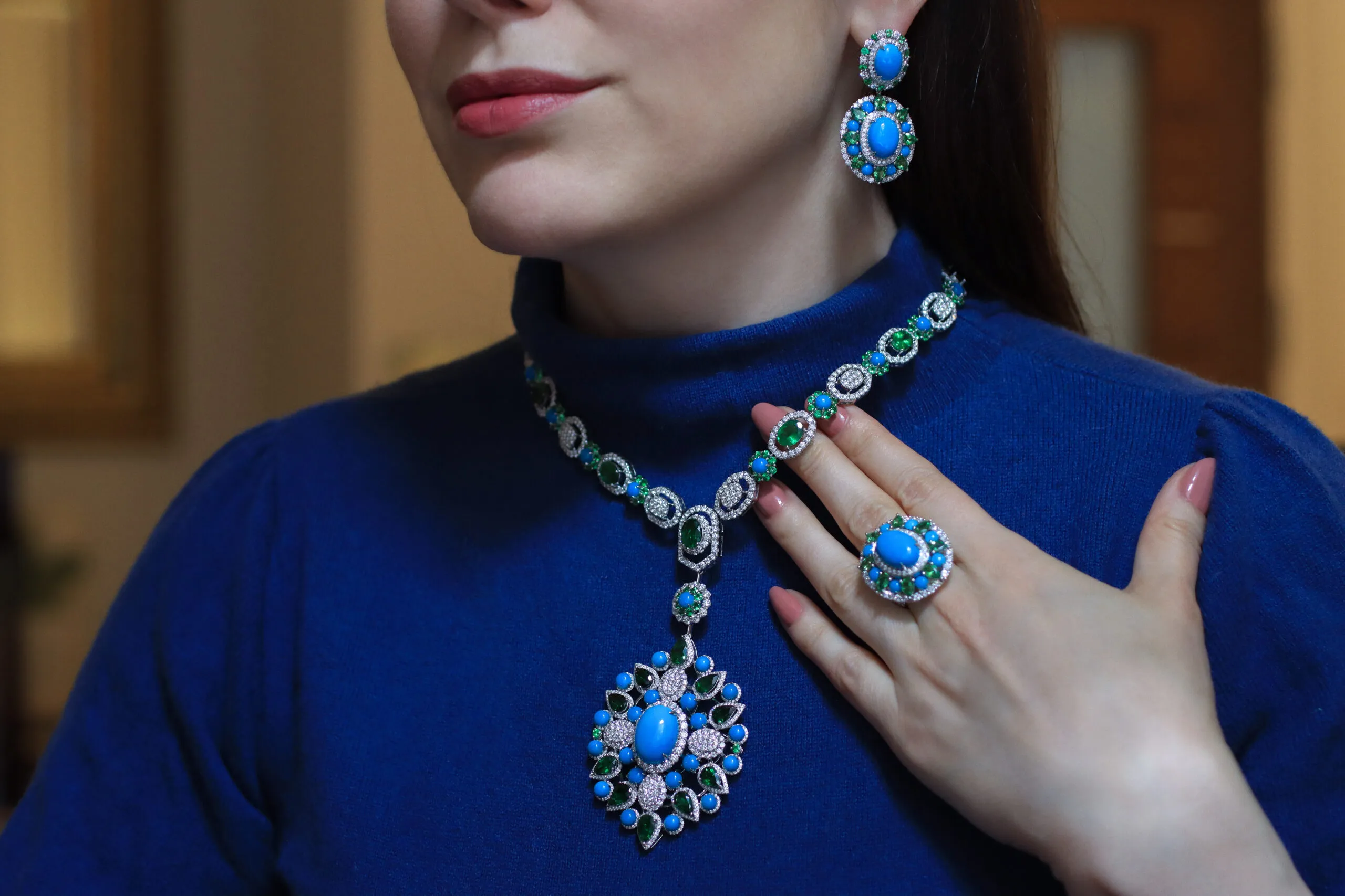Katerina Perez wears the AKANO Chikaodili suite comprising a necklace, ring and earrings set with round turquoise, tsavorite, and diamonds in 18k gold 