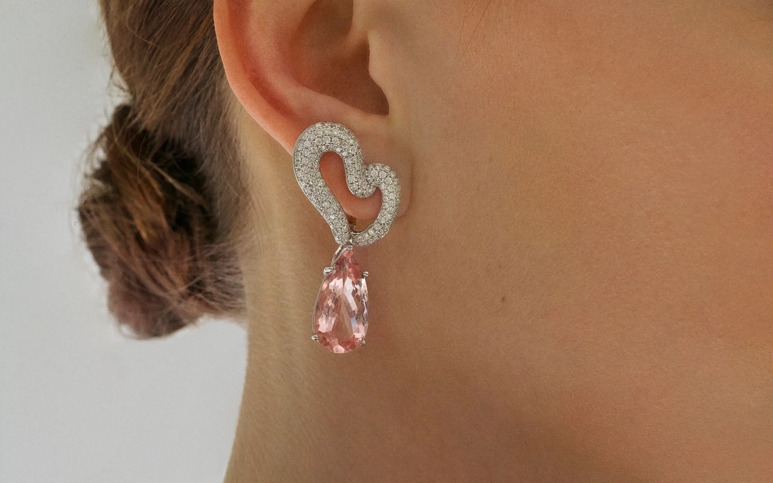 A model wears the Isabel Gemology Maria Twisted earrings with 3.04 carats of diamonds in 14k white gold, shown here with a pink gemstone drop