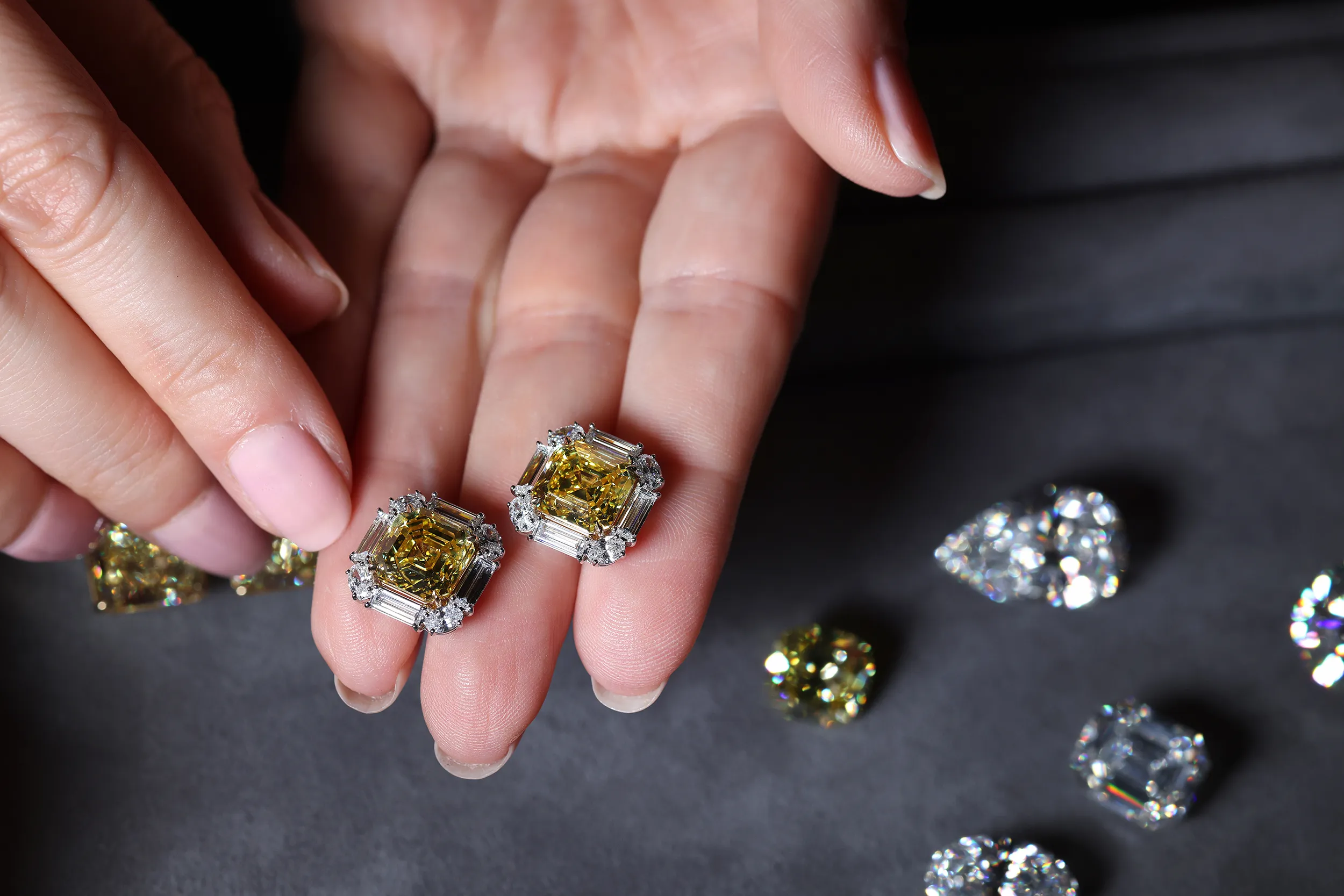 <p>Julius Klein earrings set with Vivid Yellow square emerald cut diamonds, framed by colourless baguette and oval cut diamonds</p>