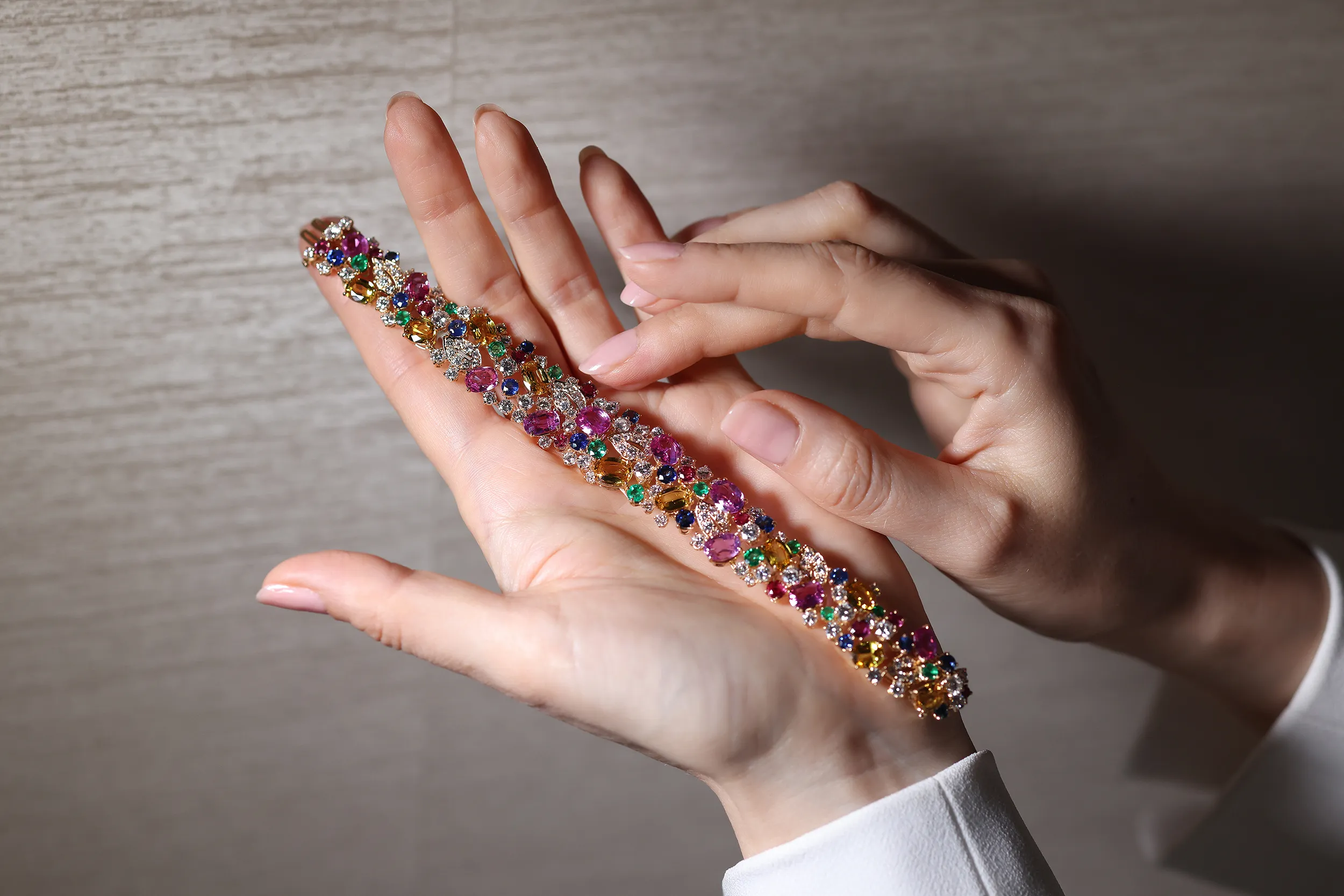 <p>An intricate mosaic of multi-coloured sapphires, rubies, emeralds and diamonds. A scatter bracelet like this can take up to six months to complete. The stone buying team collects the suite of stones, with a keen eye for balance in shape, size, cut, lustre and vibrancy. Then, the in-house lapidary matches table heights and crowns to ensure each stone is pristine</p>
