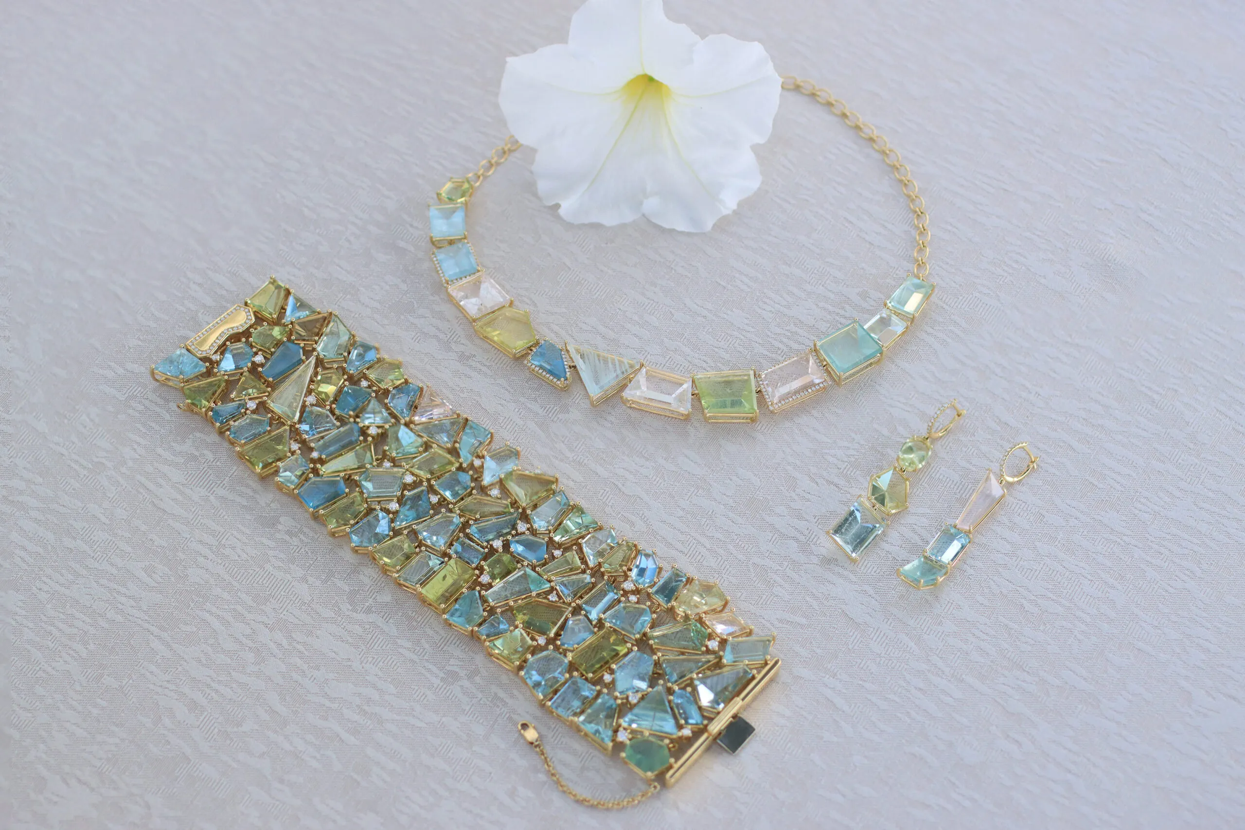 Pieces in the Lisa Nik Sparkling Mermaid collection, including a necklace, pair of earrings and a bracelet with pastel coloured beryls in 18k yellow gold 