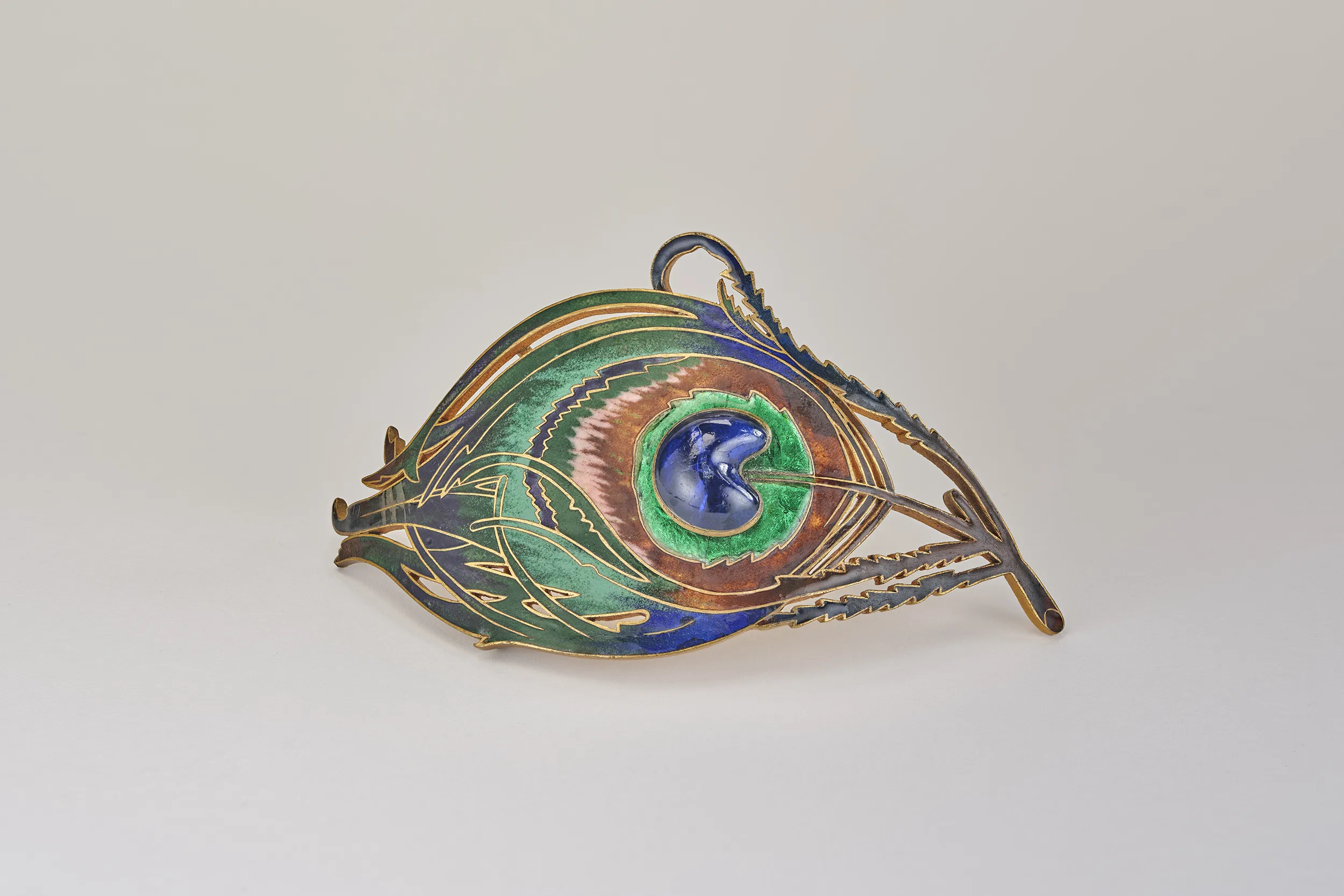 <p>A peacock feather belt-buckle, circa 1900, in cloisonné enamel on brass and glass by Piel Frères, from the L’ÉCOLE, School of Jewelry Arts’ Collection</p>