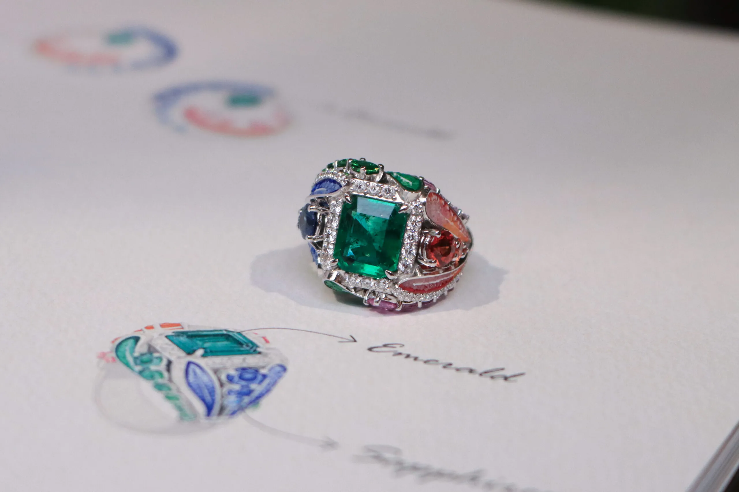 SICIS Colibrì ring with a rectangular step-cut emerald, further emeralds, diamonds, sapphires and malachite with colourful micromosaic ‘feathers’, set in white gold