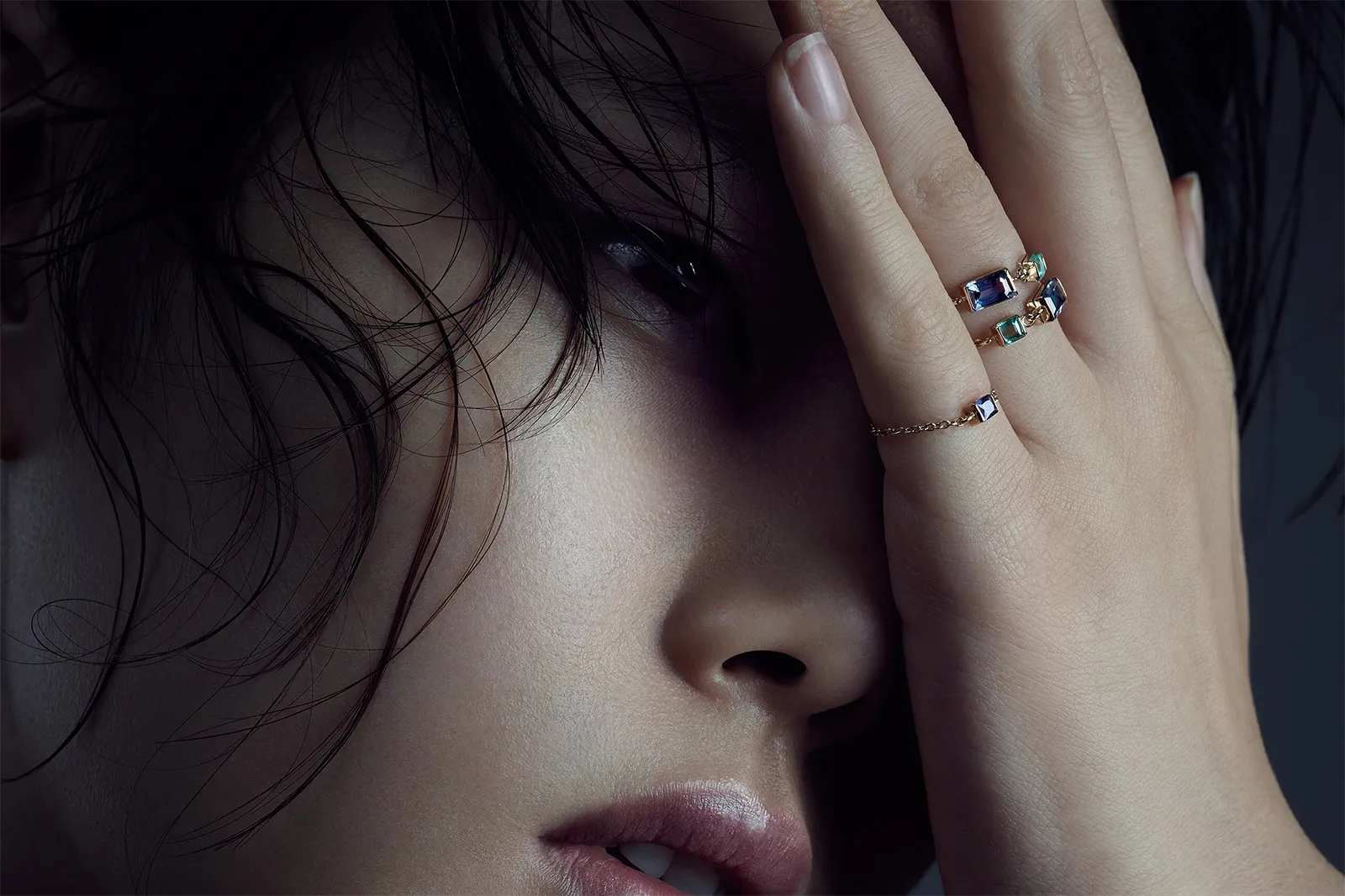 A model wears a selection of Yi Collection Chain rings with emerald and topaz set in 18k yellow gold