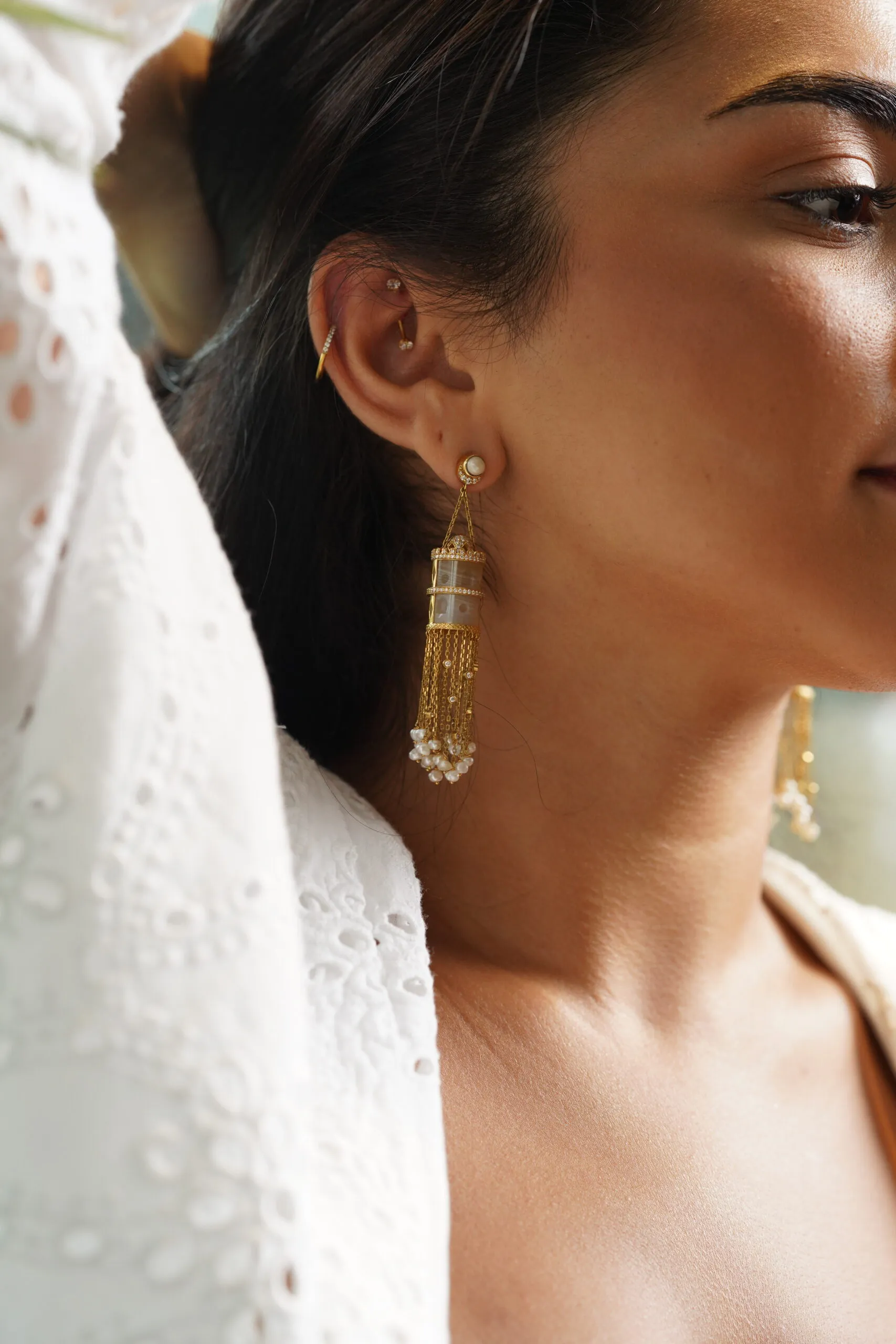 A model wears the Qasr Al Hons Agate earrings by Kyan Jewelry with carved agates, diamonds, and Bahraini natural pearls in 18k yellow gold 