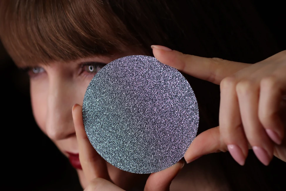 <p>Katerina Perez showcases a large disc of crystalline osmium – the rarest precious metal on earth</p>