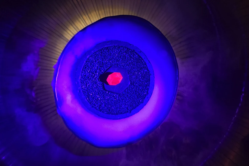 <p>A 110-carat Tajikistan spinel fluoresces with inner fire, shrouded in plumes of smoke as it emerges from a bowl of bubbling water</p>