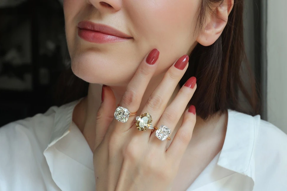 <p>Katerina Perez wearing a selection of Antique rings at Hancocks including a 13.06ct Old Mine cushion-cut diamond Solitaire ring, an 11.15ct Fancy Deep colour old-cut oval diamond ring, and a 9.01ct Asscher-cut diamond Solitaire ring</p>
