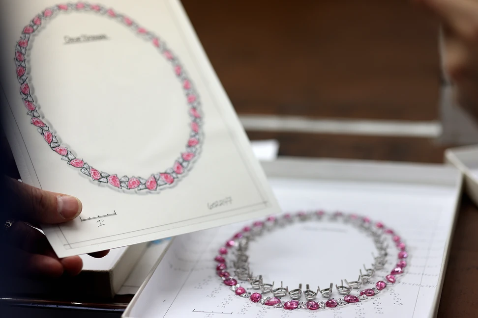 <p>The beginnings of a pink sapphire necklace. On the left is the original design drawing and on the right is a meticulous layout complete with precise dimensions and individually made settings for every stone. From there, each setting is pre-polished and then connected</p>
