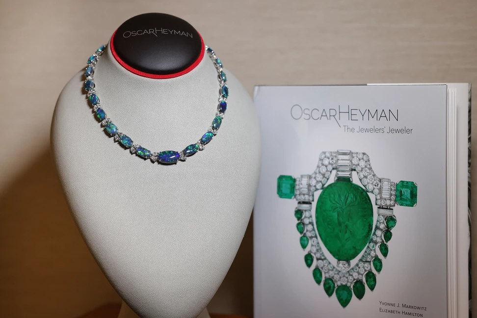 <p>Marquise diamonds sit between an impressive 25 oval opals totalling over 65 carats in this luxurious necklace that glows with greens and blues. Next to it, a book honouring and celebrating the history of Oscar Heyman, written and published by the Museum of Fine Arts, Boston</p>
