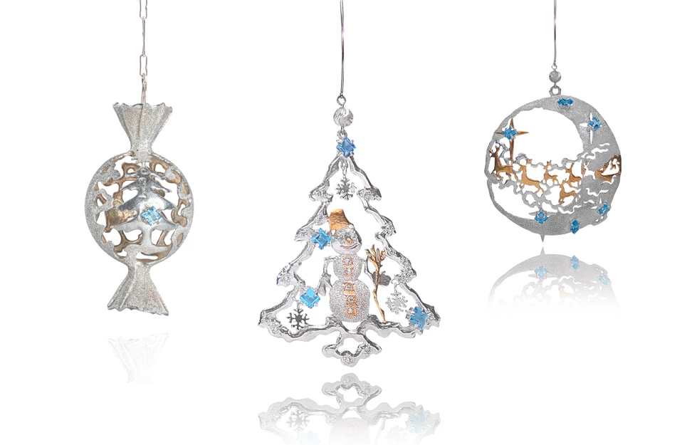 <p>Marilisi silver Christmas ornaments, featuring a candy, a snowman nestled within a Christmas tree, and a herd of reindeer</p>