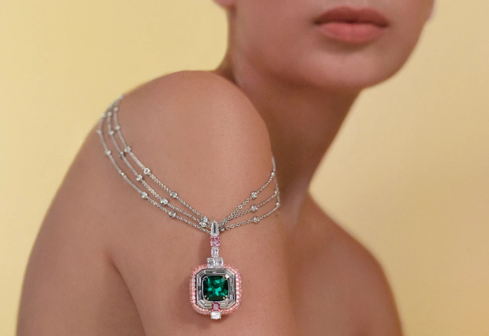 <p>Model wearing the Muzo Emerald Colombia Earth Magic II necklace in gold, platinum, a 7.66-ct Muzo emerald, a 1.06 carat fancy intense purplish pink Argyle diamond, 0.43 carat, a fancy purplish red Argyle diamond and white diamonds from the Green Jewel Tradition collection</p>