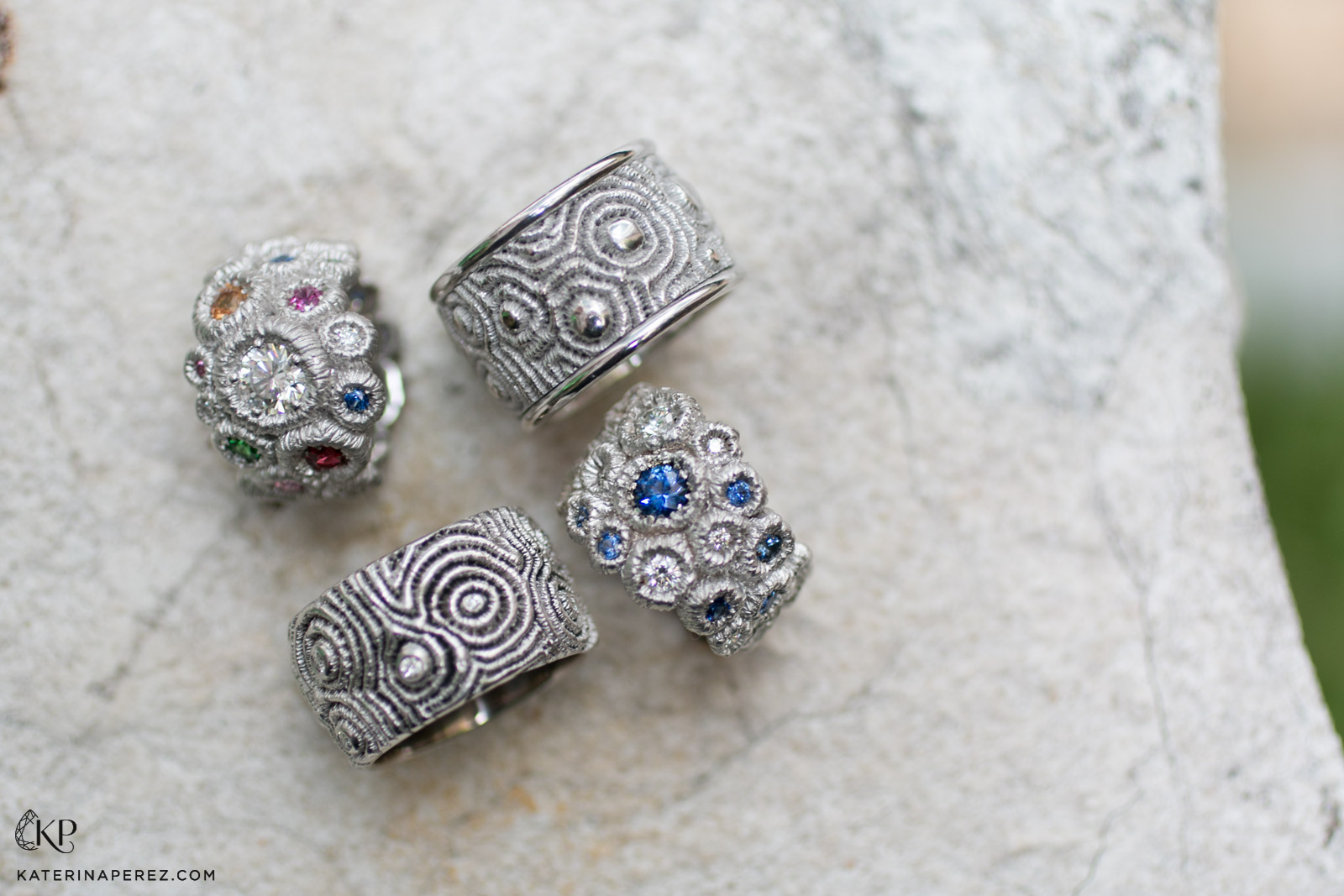 Clockwise from top left; ring in White Gold with a 0.74ct Brilliant Cut Diamond and 7 diamonds totalling 0.245 ct, with tsavorite, sapphire and ruby, ring in White Gold, ring in White Gold with 13 Brilliant Cut Diamonds totalling 0.268ct, a diamond of 0.175ct and 24 Sapphires totalling 1.735ct, and ring in White Gold with 12 Brilliant Cut diamonds totalling 0.255ct