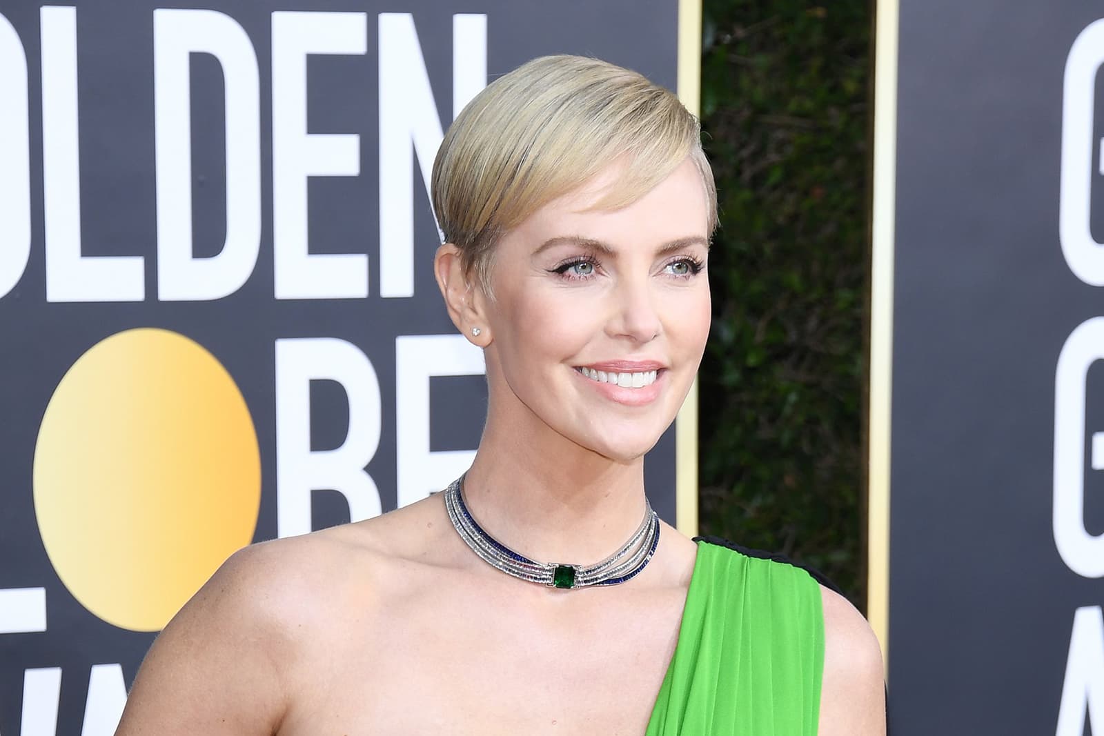 Charlize Theron wearing Tiffany & Co. choker with central emerald, diamonds and sapphires set in platinum and stud earrings with diamonds