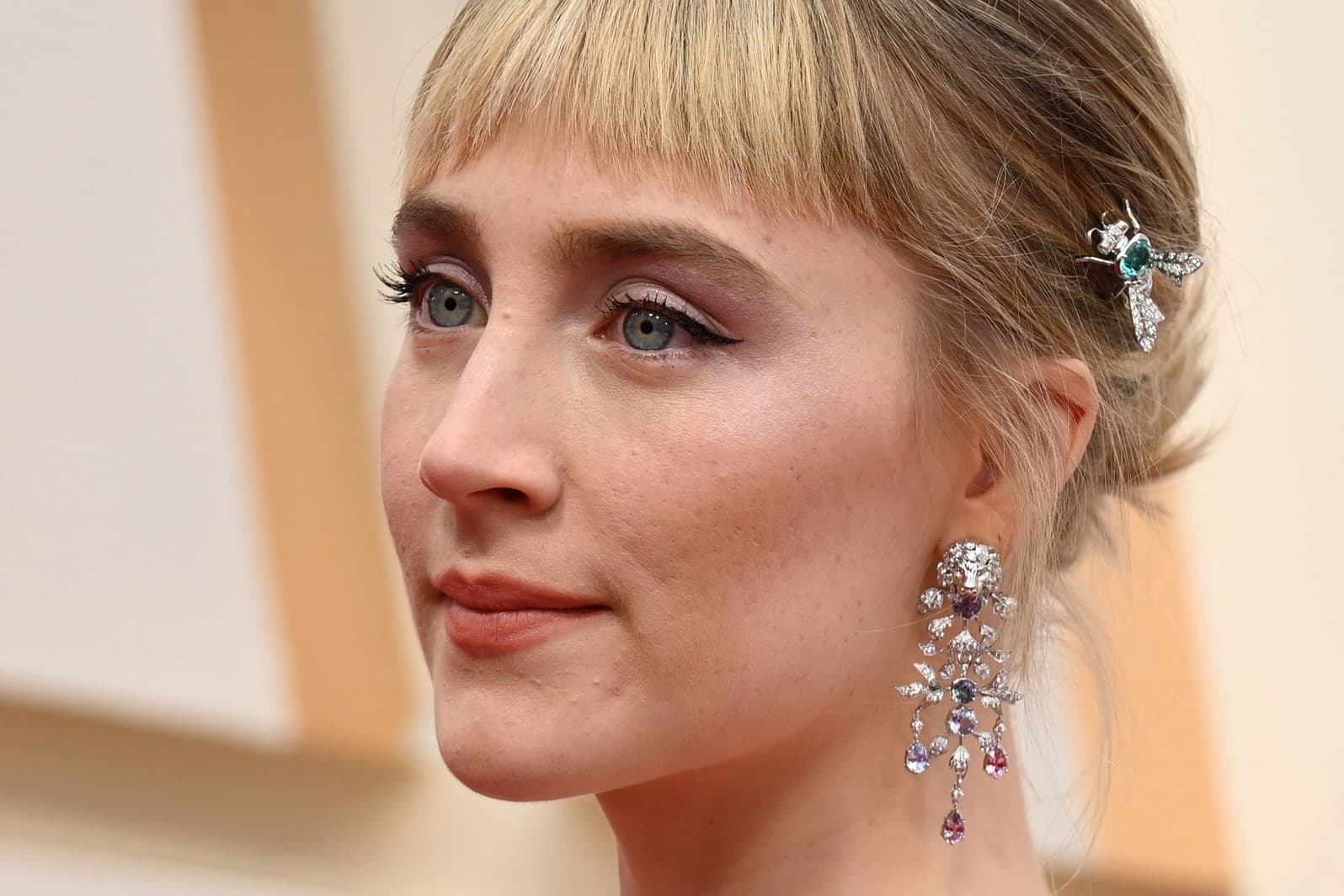 Saiorse Ronan wearing Gucci Animal Kingdom collection brooch in the hair with topaz and diamonds, and earrings with sapphires and diamonds, both in white gold