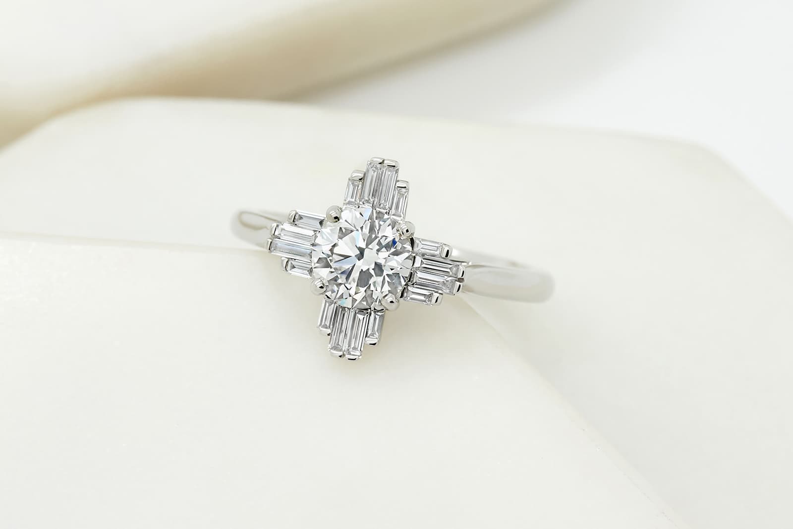  Taylor & Hart Art Deco-inspired round diamond engagement ring with diamond baguettes positioned at the four cardinal directions