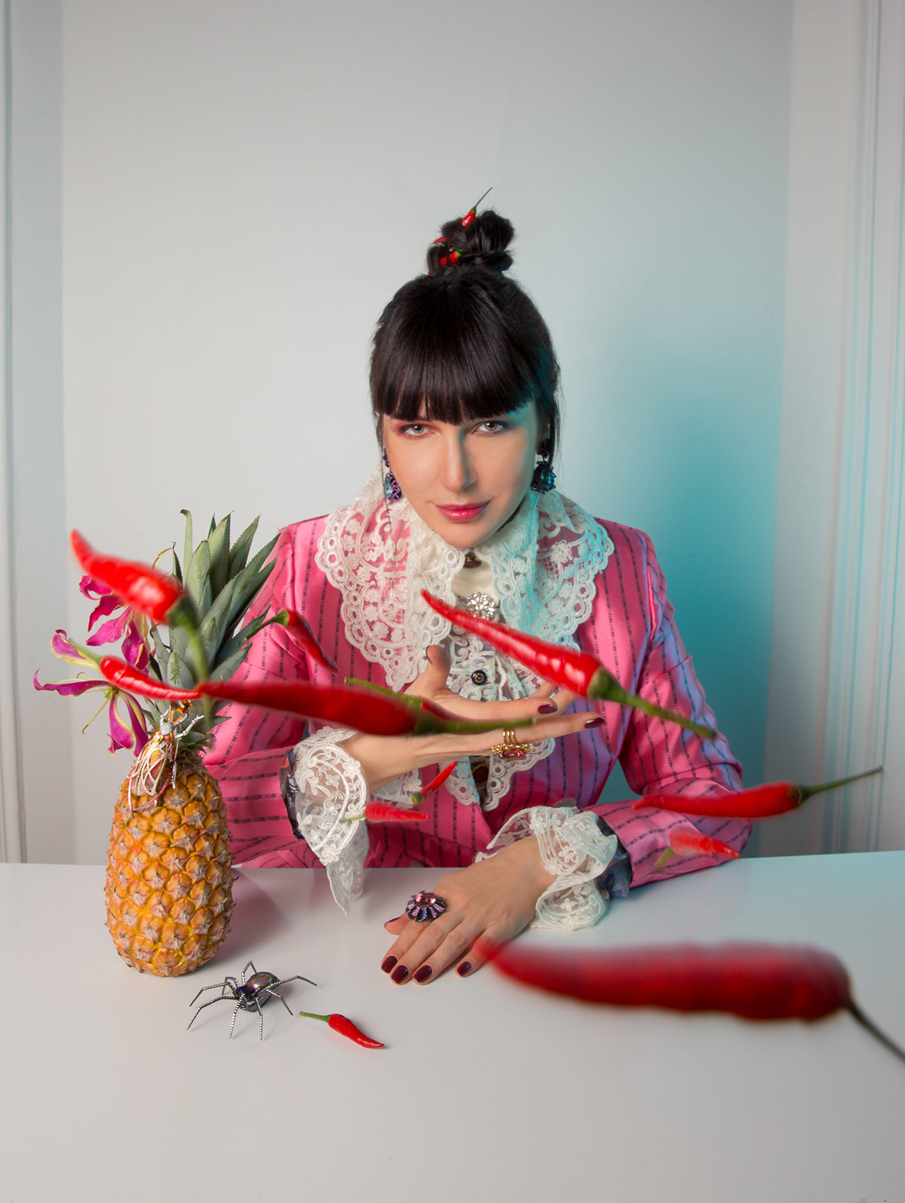 Katerina wears earrings and rings by Lorenz Baumer, blouse by Etienne Jeanson and a blazer by Collini Milano, with the Araignée Extravagante Good Girl Bad Girl spider-inspired brooch crawling along the table 