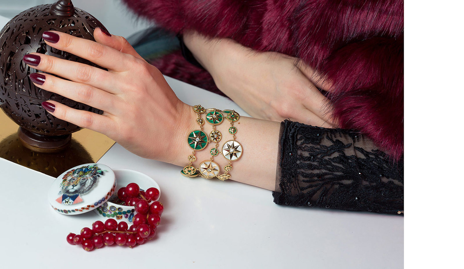 Кафф-браслеты Dior Joaillerie Rose des Vents из желтого золота с бриллиантами, изумрудами, перламутром и малахитом в сочетании с платьем и накидкой от Promulias