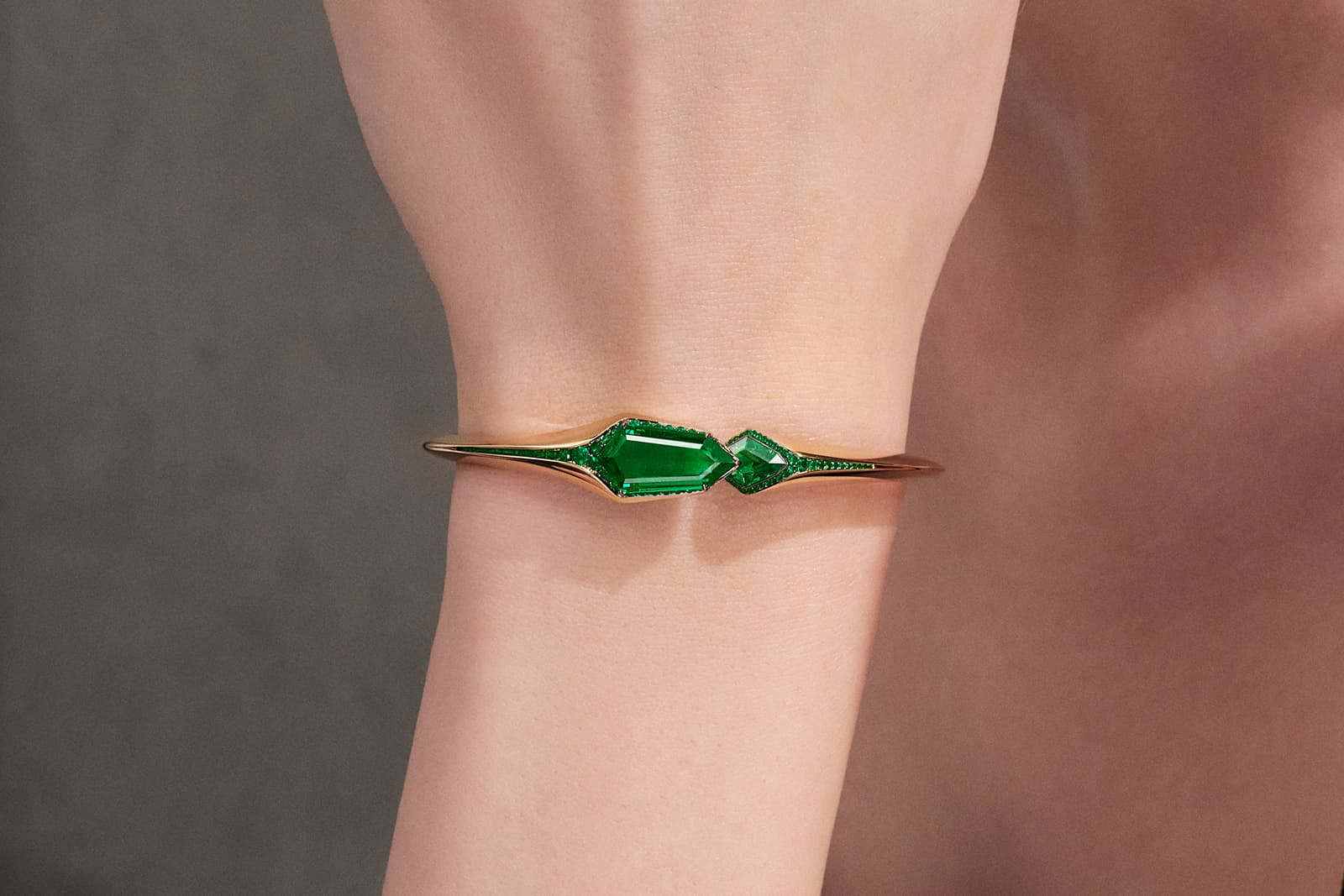  This FORMS MUSE Colombian emerald bangle is set with two shield-shaped emeralds and fine rows of melee emeralds 