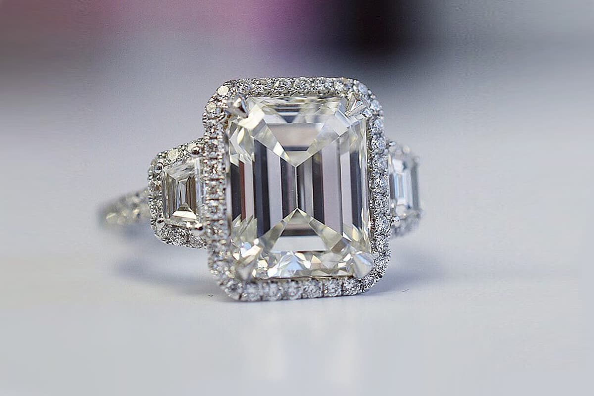  IceRock Diamonds three-stone emerald-cut diamond engagement ring with a subtle diamond halo