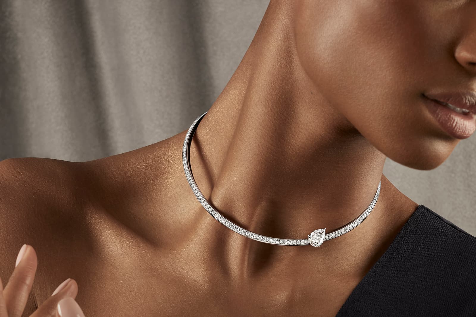 A model wears the Thelma West Apòstrofe necklace with a pear-shaped diamond and round brilliant-cut diamonds