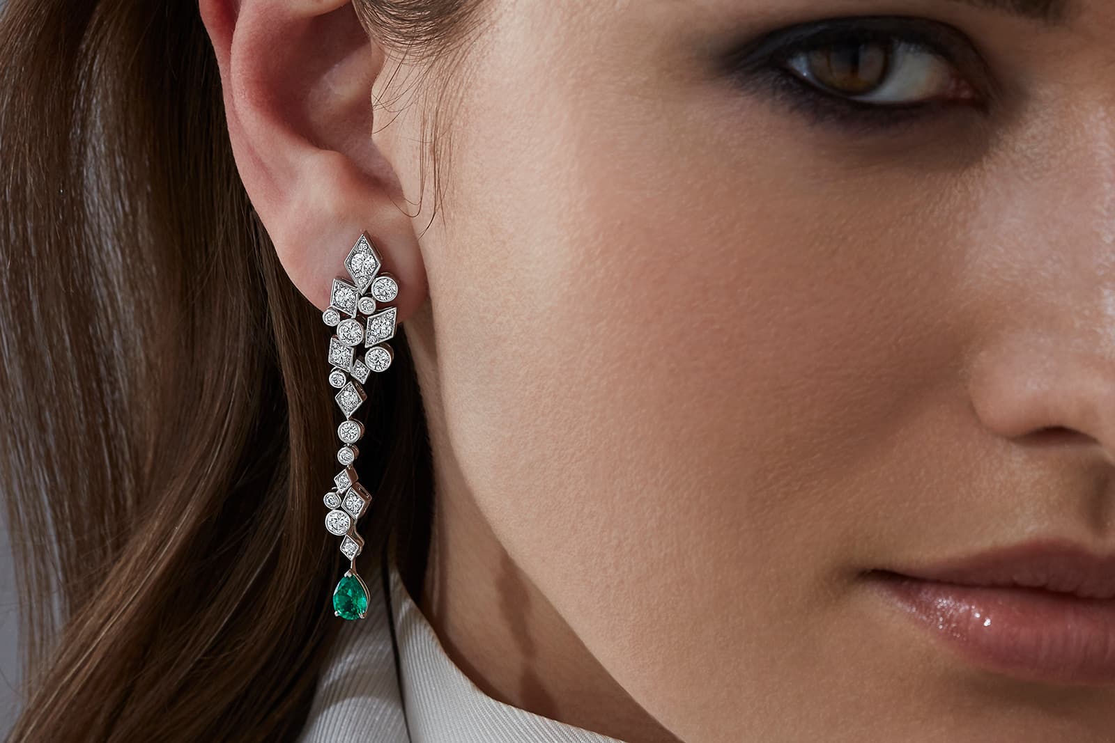  A model wears the Garrard Albemarle diamond earrings in 18k white gold with the detachable pear-shaped emerald drops