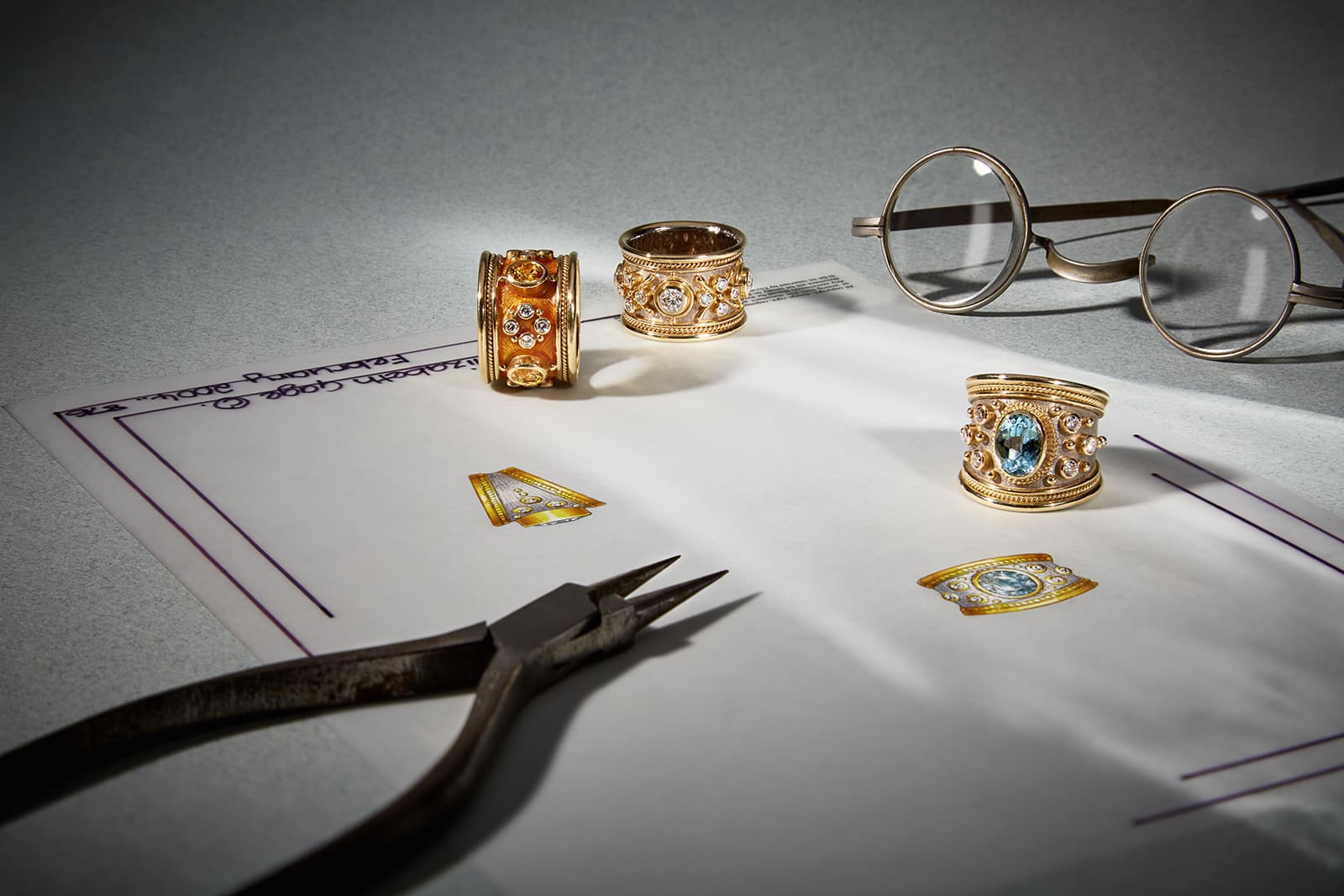 Elizabeth Gage Templar Band ring with pale tangerine enamel, alongside a diamond-set Templar Band and an aquamarine and diamond Tapered Templar ring  