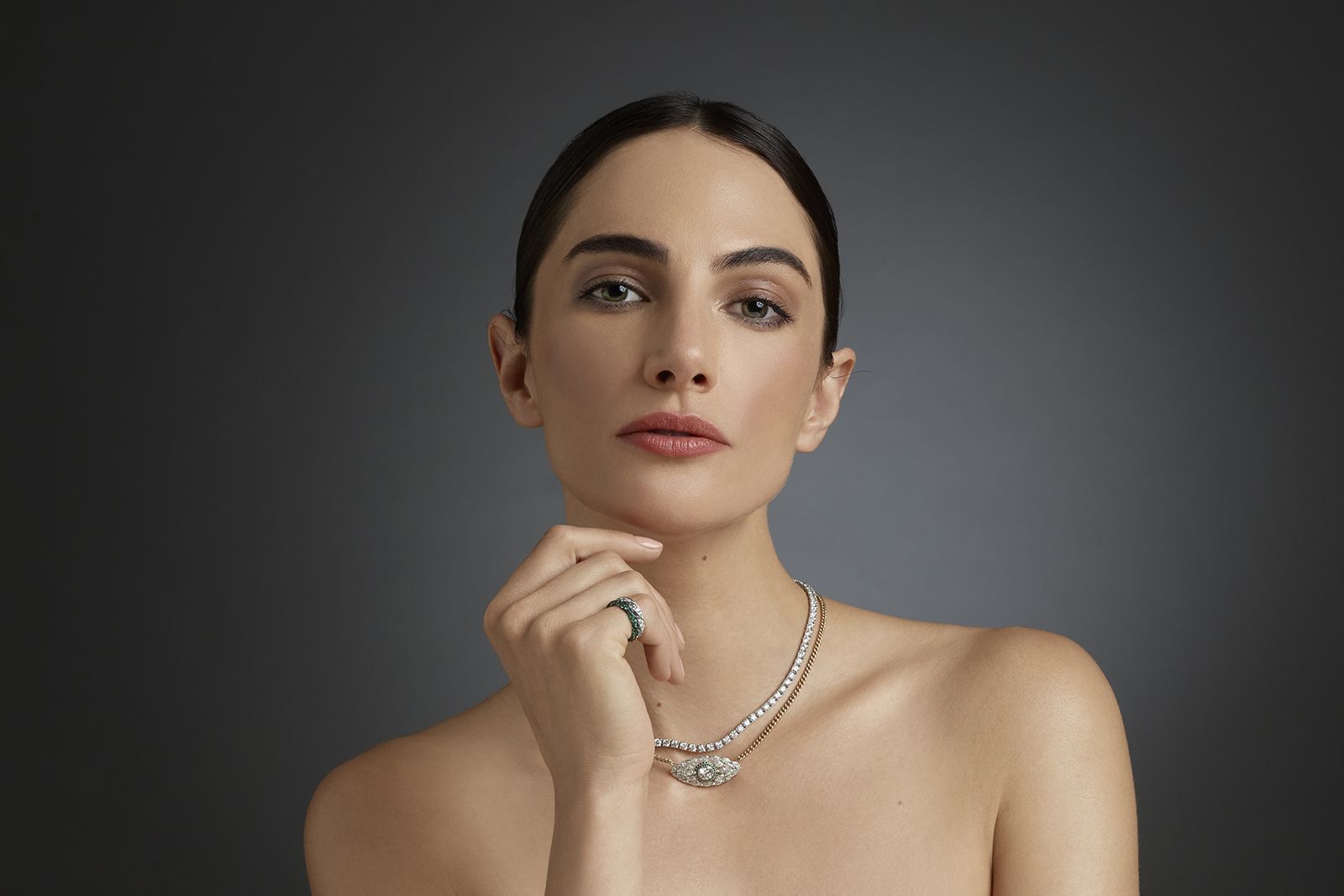  A model wears D. GREGORY jewellery, including the Riviere necklace, the Evil Eye necklace and two Vesper 1 rings with diamonds in platinum and emerald in yellow gold 