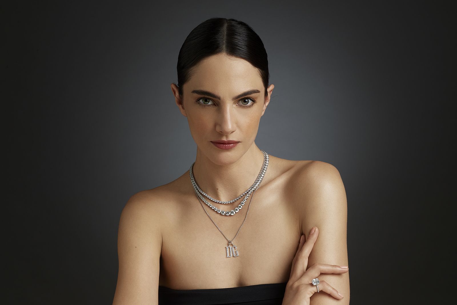 A model wears D. GREGORY jewellery, including the Riviere necklace with diamonds in platinum, the Riviere Gradual necklace with diamonds in platinum and an Elizabethan Letters pendant with the initials ‘D’ and ‘G’ set with diamonds