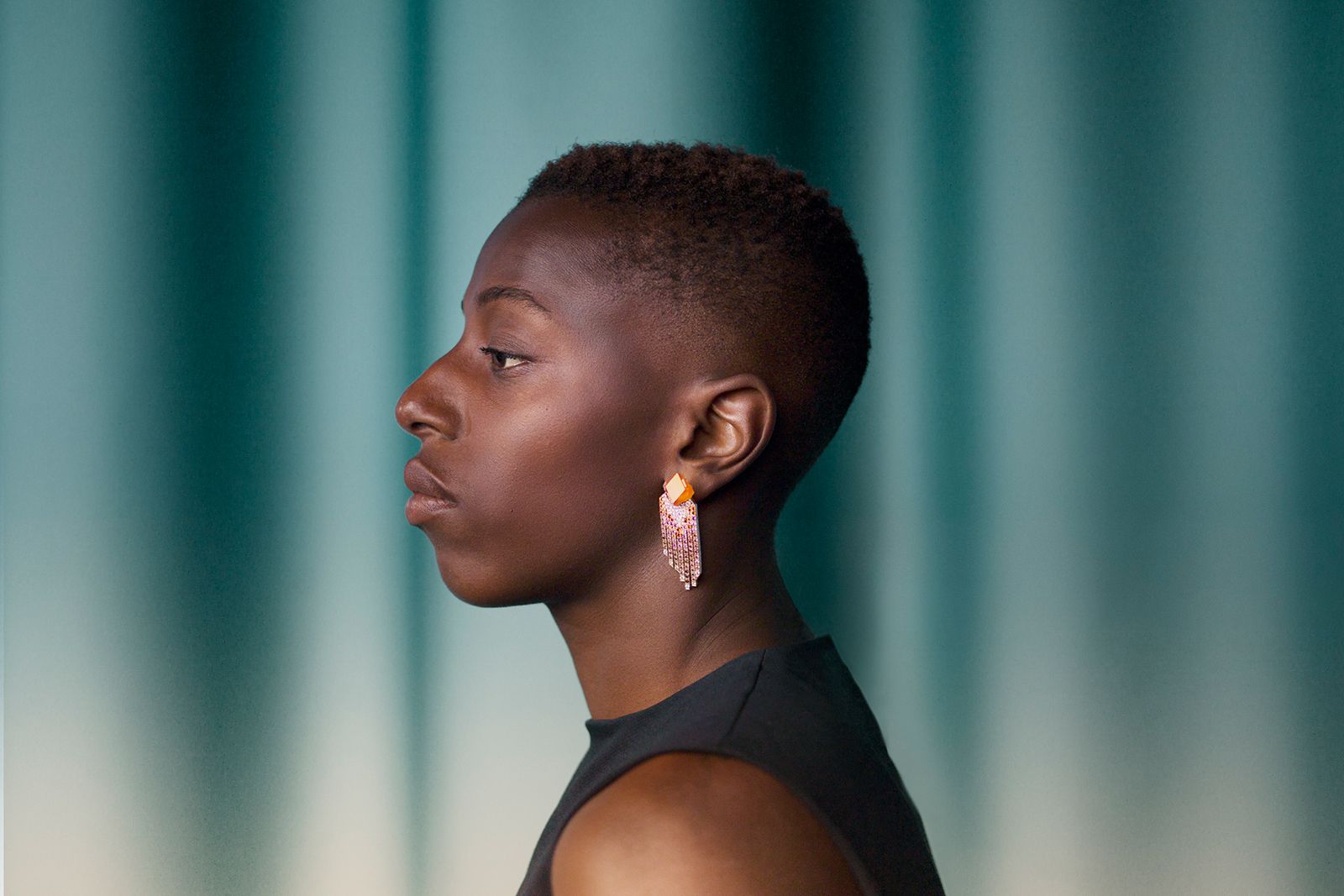 A model wears the Hermès Lumières brutes earrings in rose gold with two rough spessartite garnets and a shadow of spessartite garnets and rhodolites, diamonds, orange-yellow diamonds and brown diamonds from the Les Jeux de l'ombre High Jewellery collection