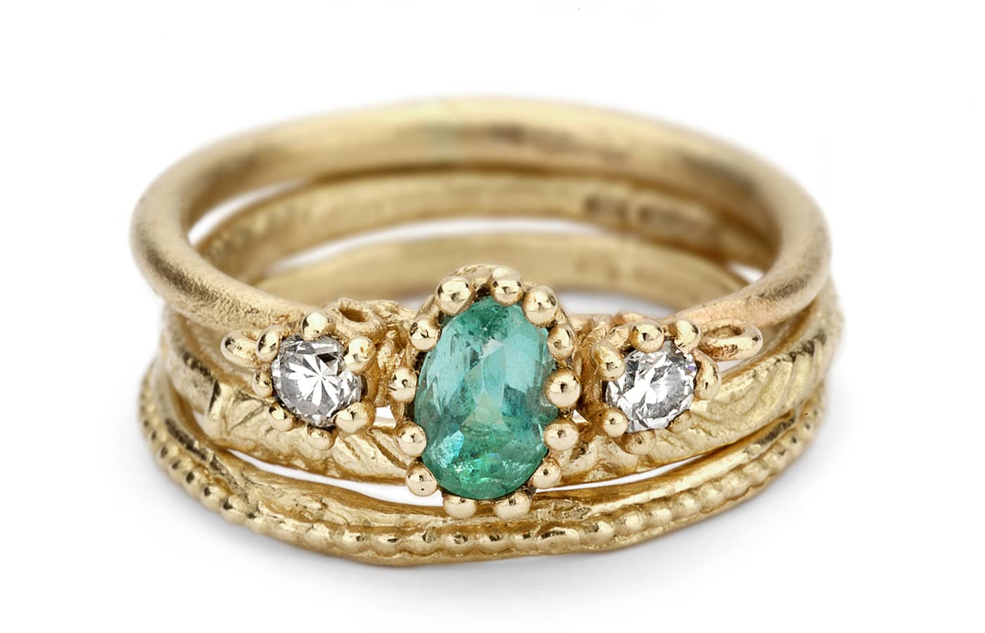  A stack of 14k yellow gold Ruth Tomlinson rings, with one ring set with a 0.5ct emerald and two diamonds 