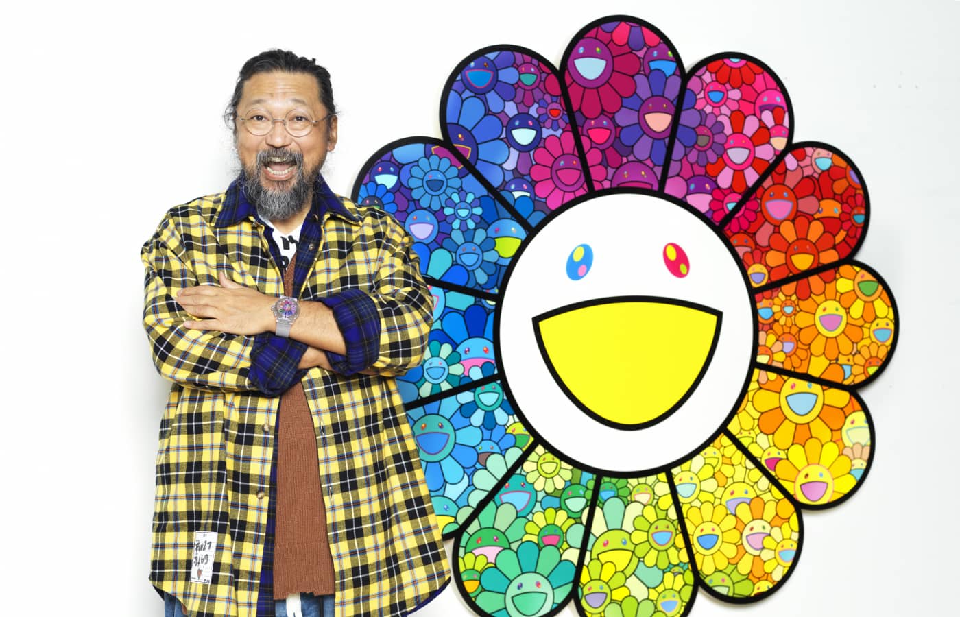  Artist Takashi Murakami posing along side his artwork