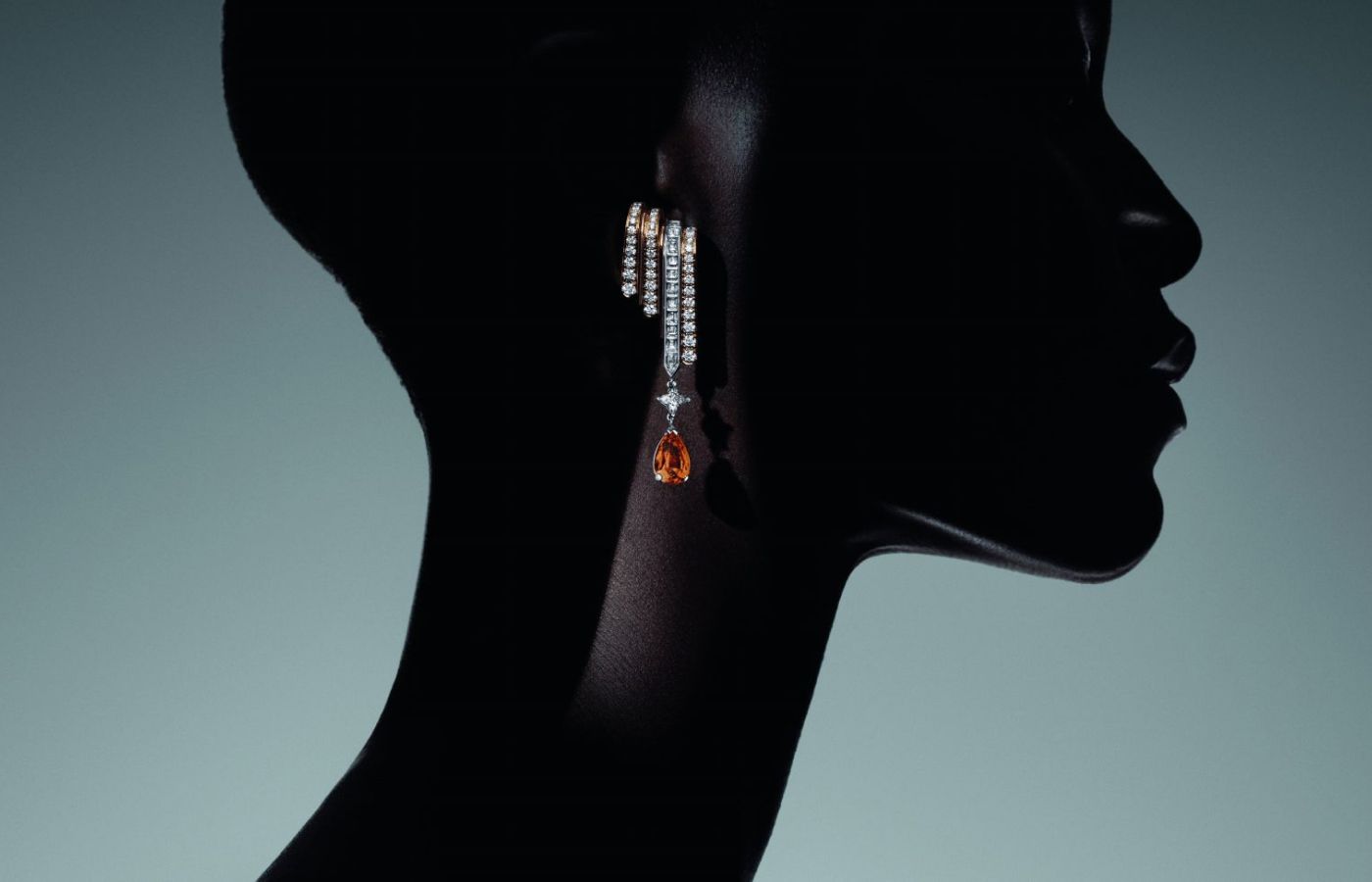 Model wearing Louis Vuitton Volcano High Jewellery earrings in gold, platinum, 4.18-ct spessartite Mandarin garnets, LV Monogram Star cut diamonds and diamonds from the Deep Time High Jewellery Collection
