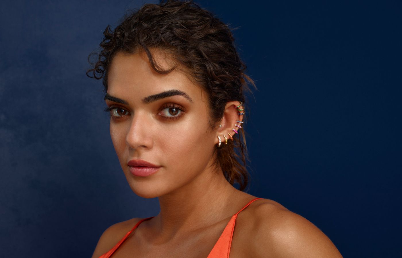  A model wears a stack of Orb Hoop earrings in a variety of diamond and gemstone finishes by Robinson Pelham