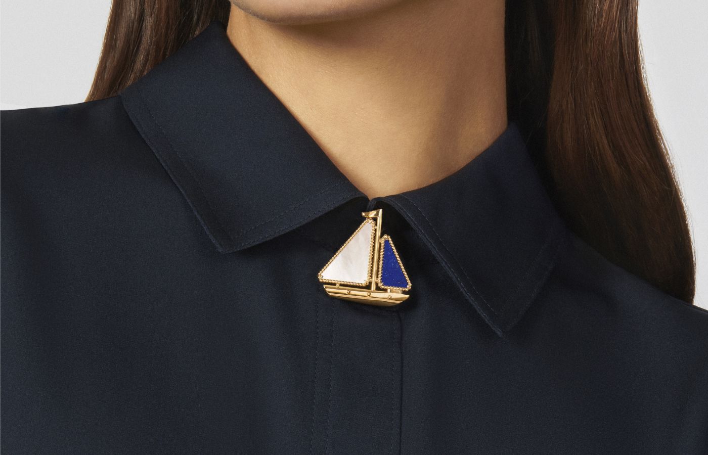Model wearing Van Cleef & Arpels Lucky Summer Boat clip in gold, lapis lazuli and white mother-of-pearl from the Lucky Summer collection