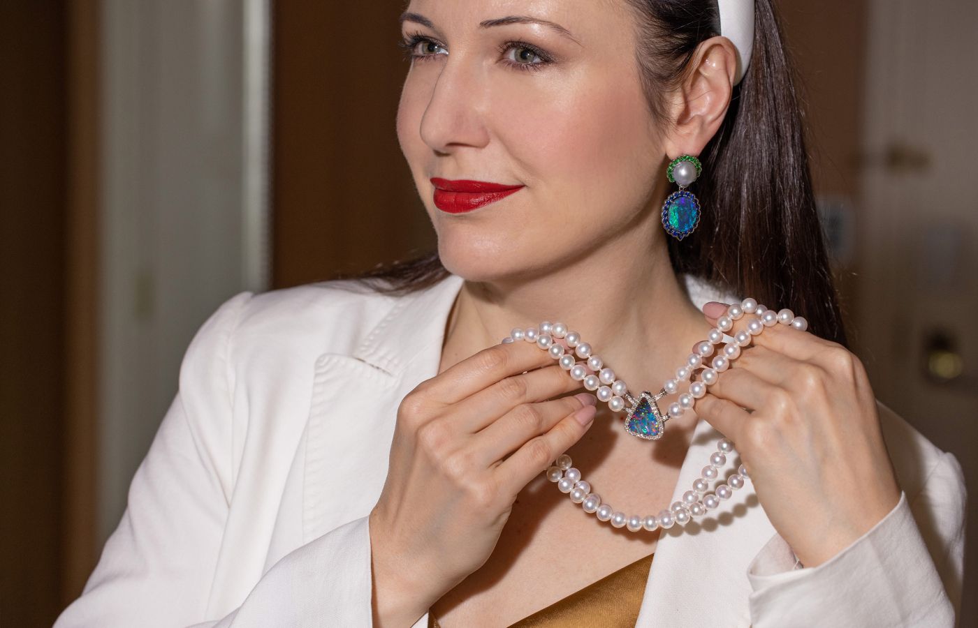 Katerina Perez wears a pair of Cindy Xu black opal and South Sea pearl drop earrings with tsavorites and sapphires in 18k white gold while showcasing a multi-row pearl and black opal necklace 