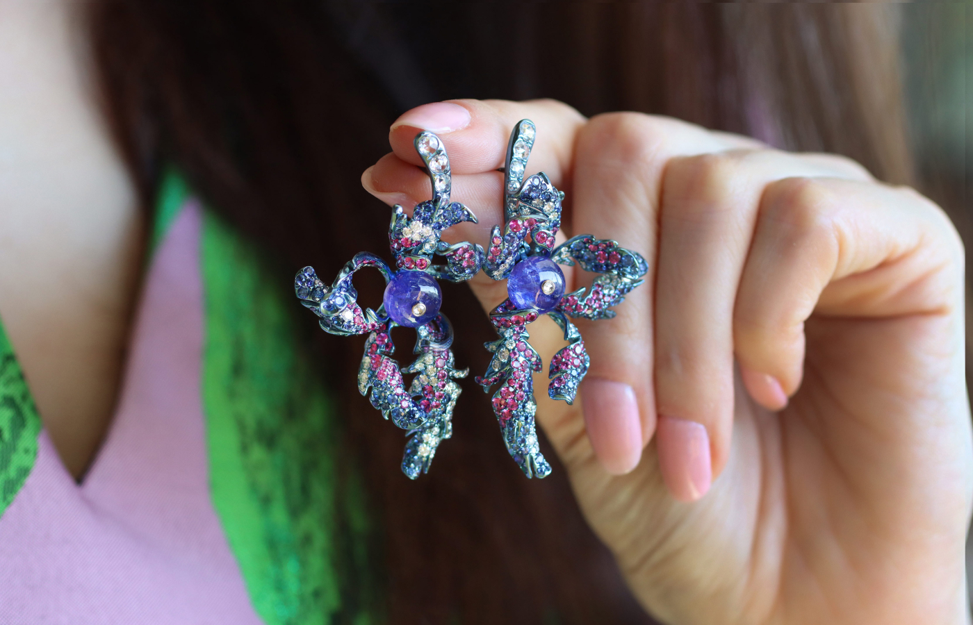 Katerina Perez holding the Monal earrings in tanzanite, multicoloured gemstones and diamond by Neha Dani