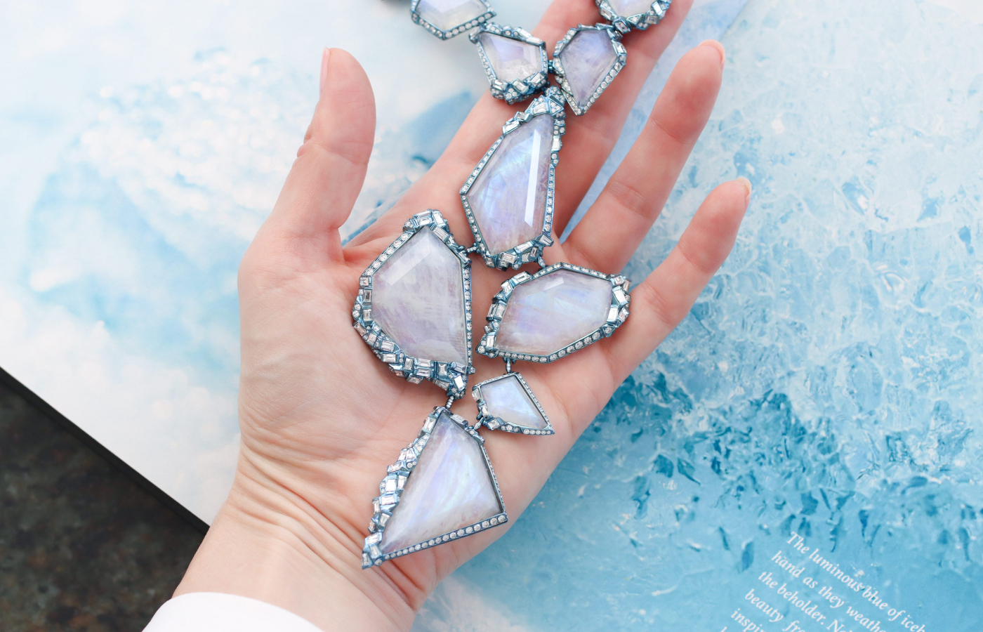 Katerina Perez holding the Neha Dani Tazlina Glacial necklace in blue moonstone and diamond